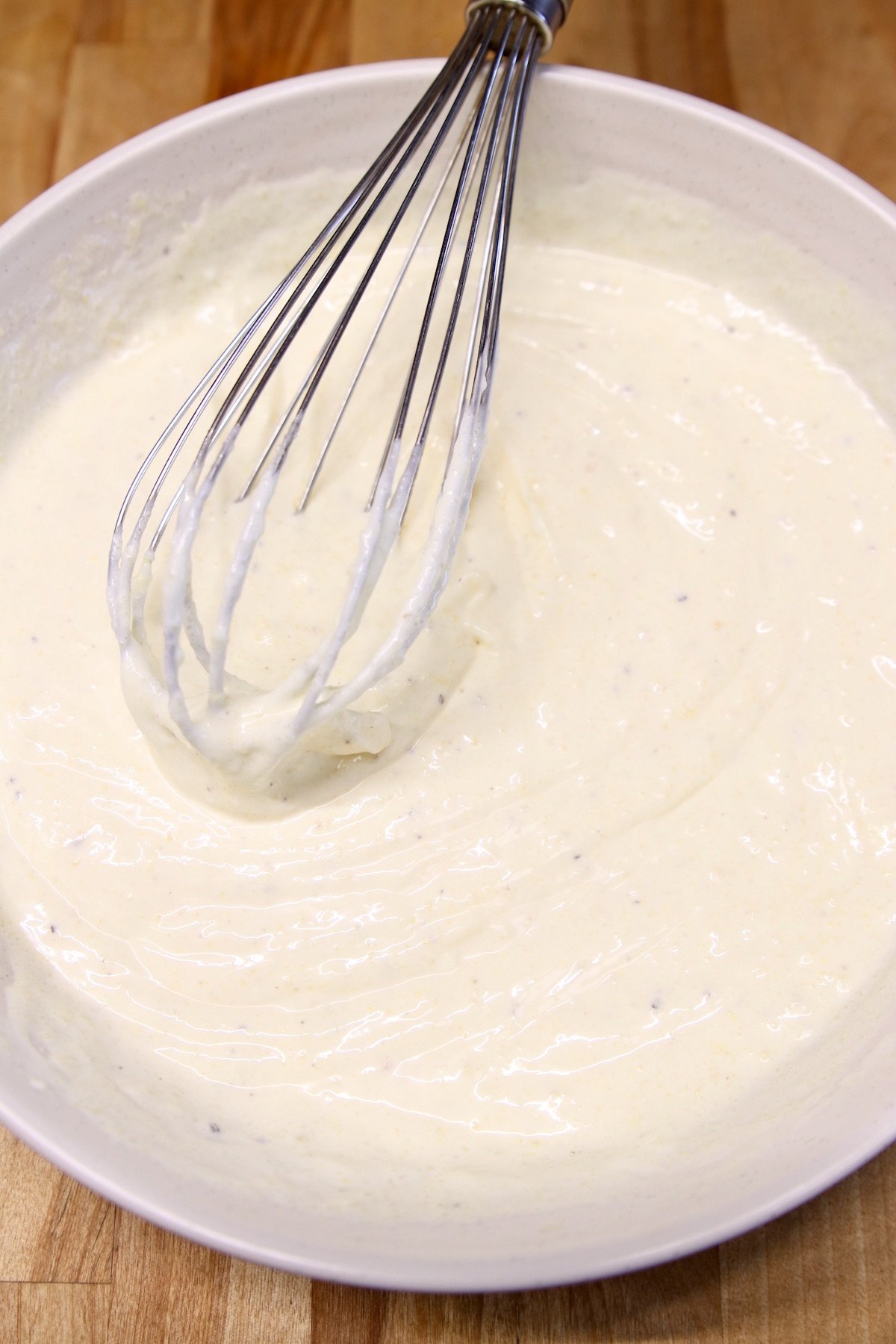 cream sauce in a bowl with whisk