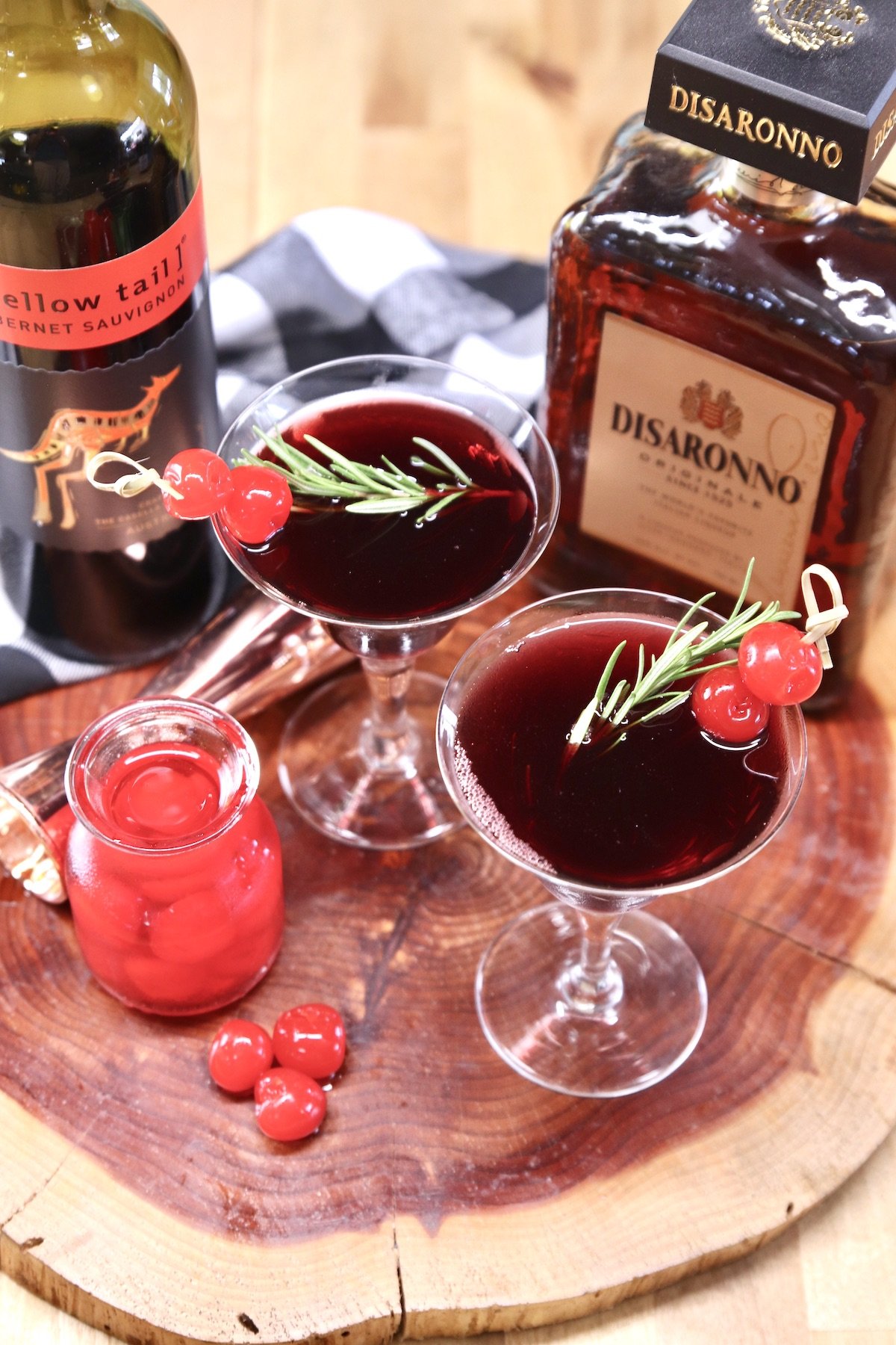 red wine and Amaretto cocktail on a wood board with maraschino cherries