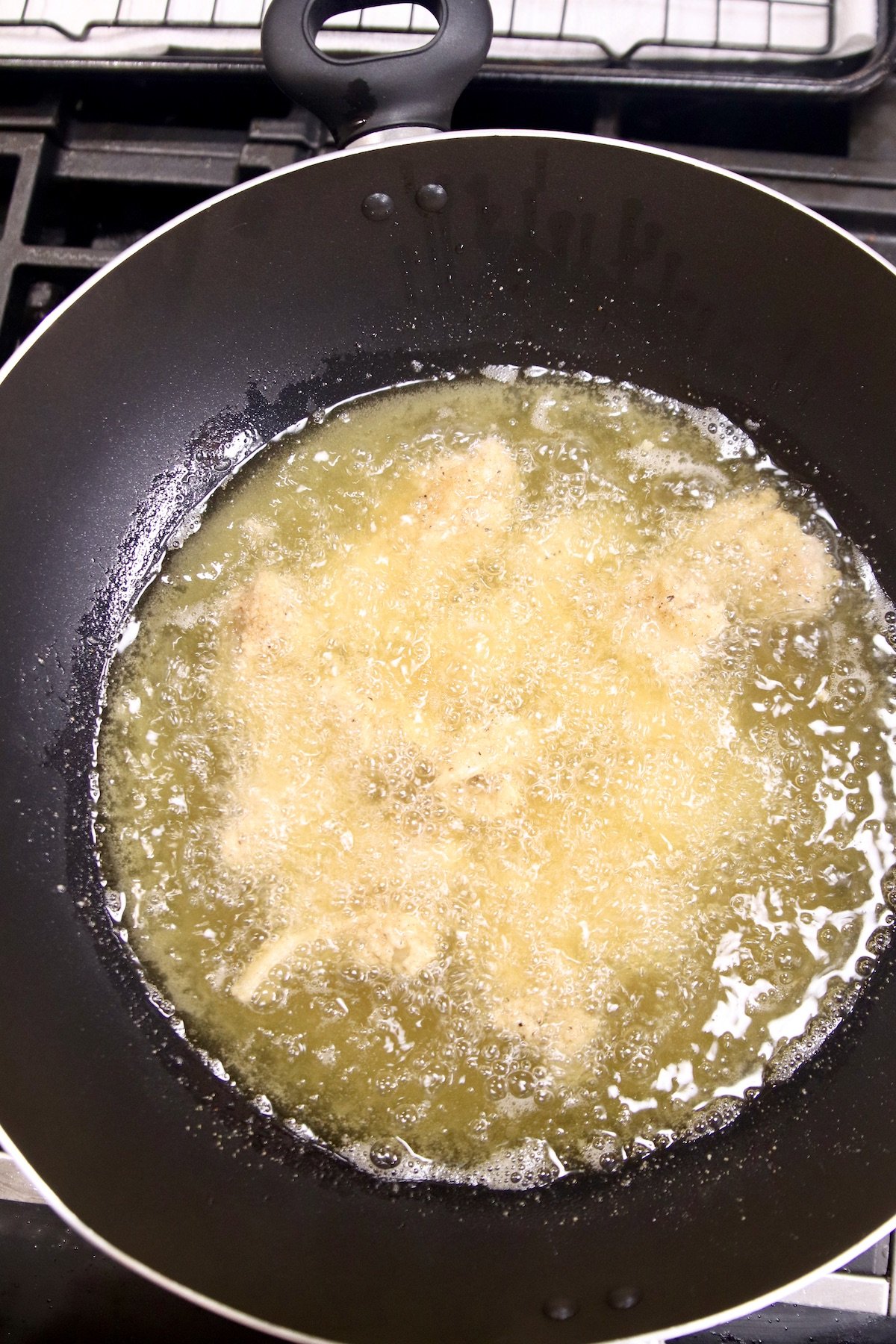 Frying chicken pieces in a wok with vegetable oil