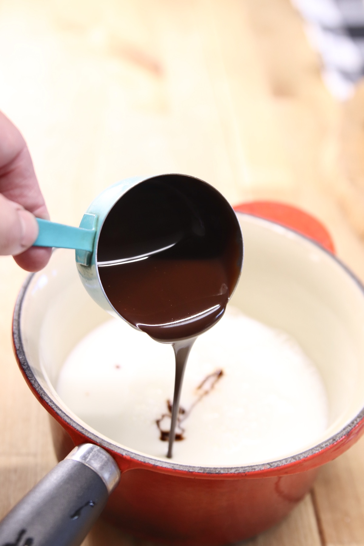 adding chocolate syrup into a small pan with milk