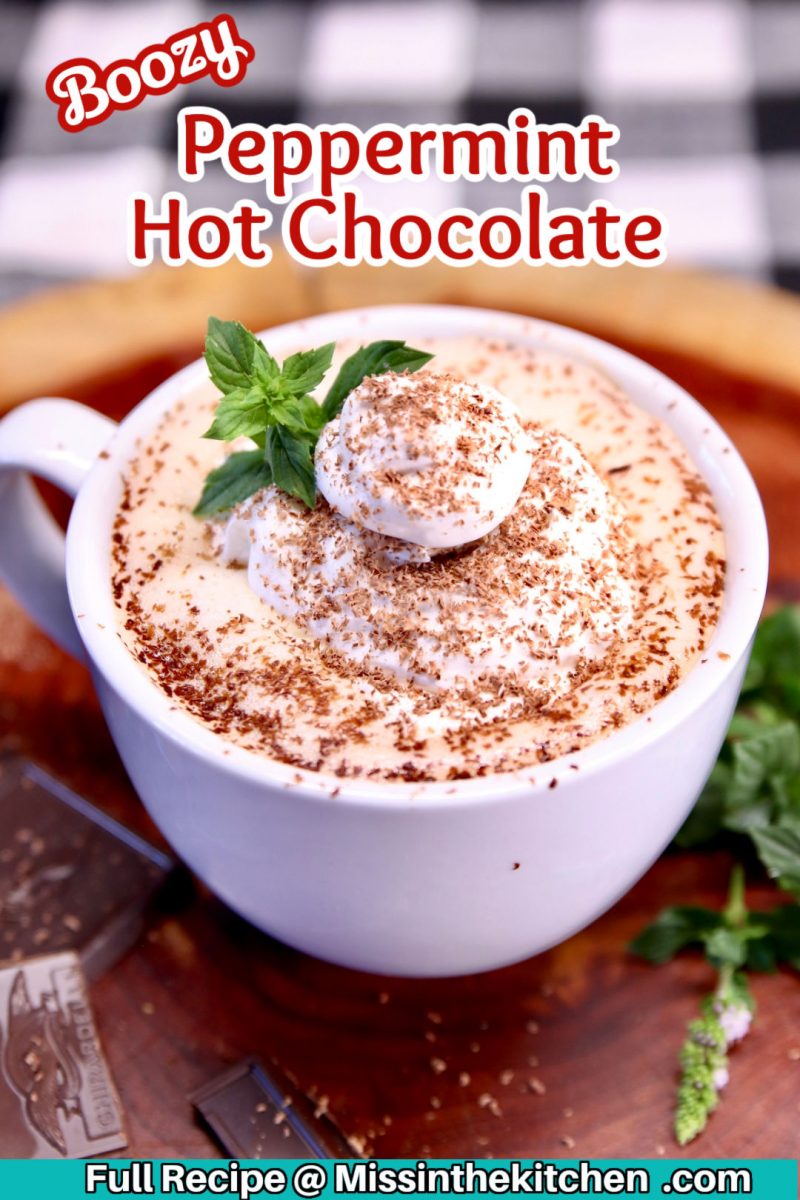 boozy peppermint hot chocolate in a mug with whipped cream, shaved chocolate and a mint sprig