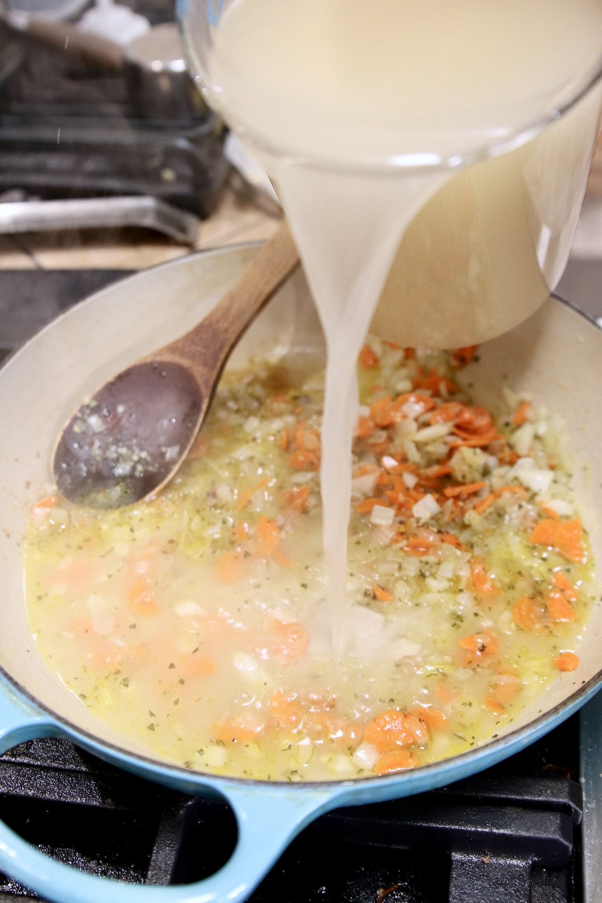 pouring chicken broth into chicken soup