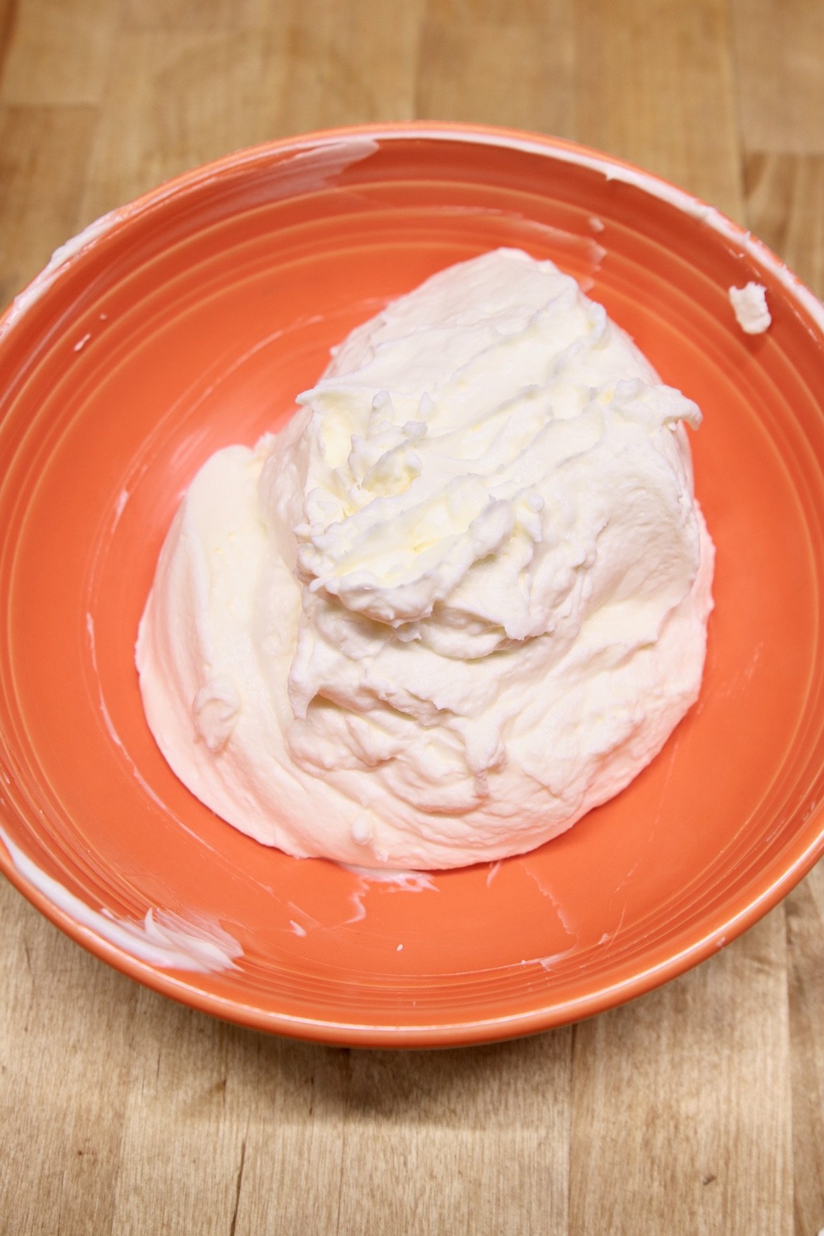 whipped cream cheese and powdered sugar in an orange bowl