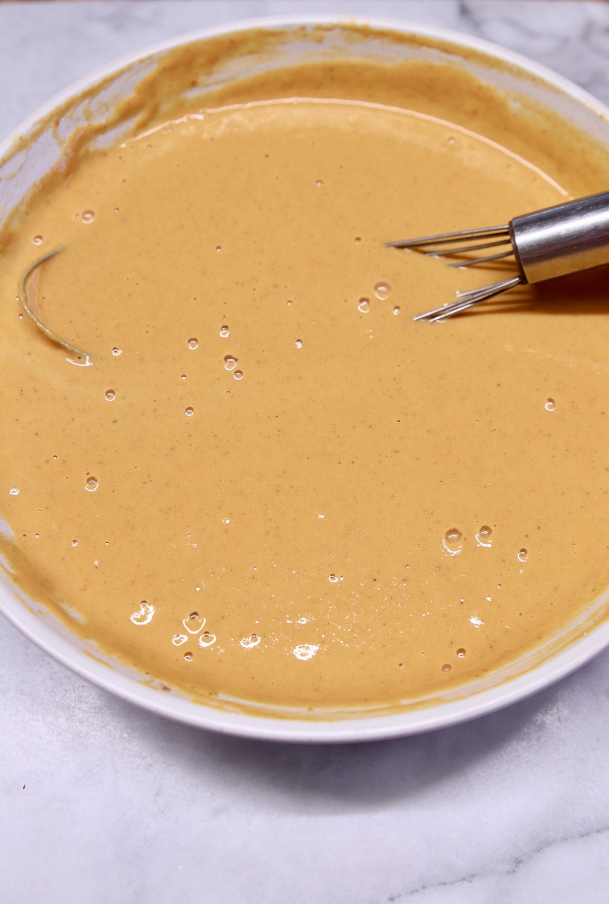 Pumpkin pie filling in a bowl with a whisk