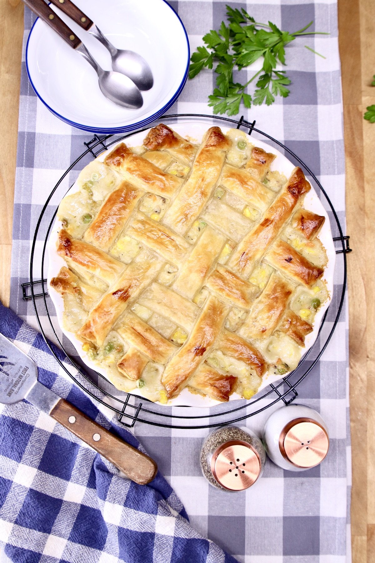 chicken pot pie on a checked table runner with bowls, spoons, salt and pepper shakers