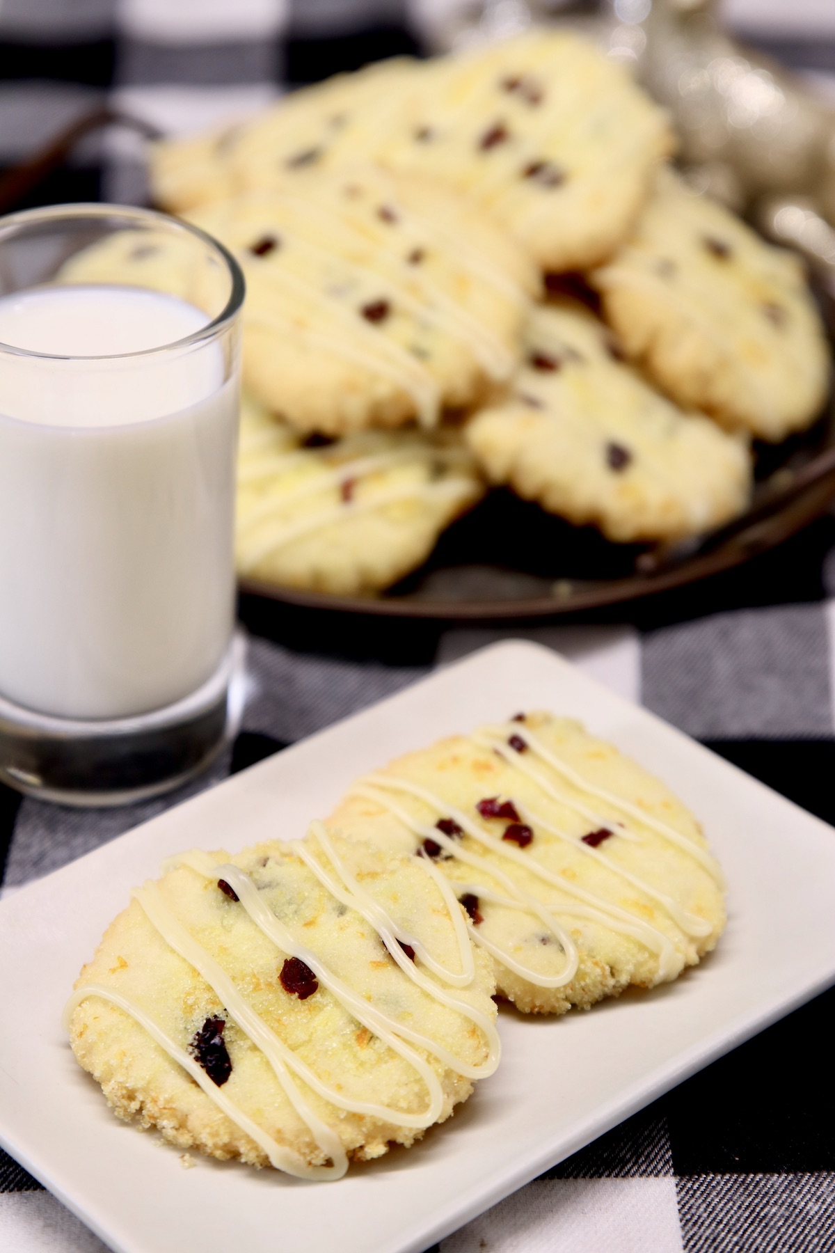 plate of 2 cranberry cookies, milk and platter of cookies