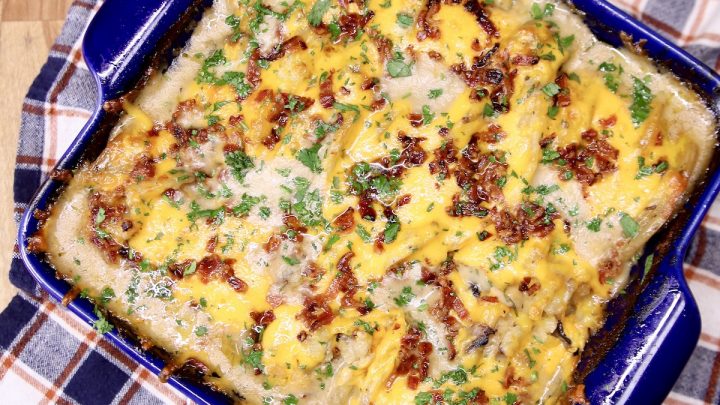 potato casserole with cheese and bacon in a blue square baking dish
