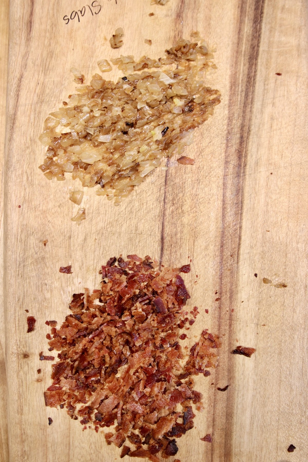 minced caramelized onions and chopped bacon on a cutting board