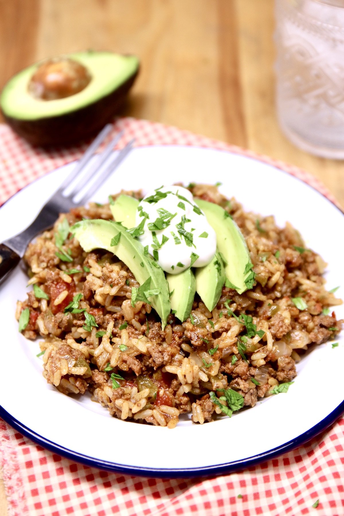 plate of Spanish rice with sliced avocado, sour cream