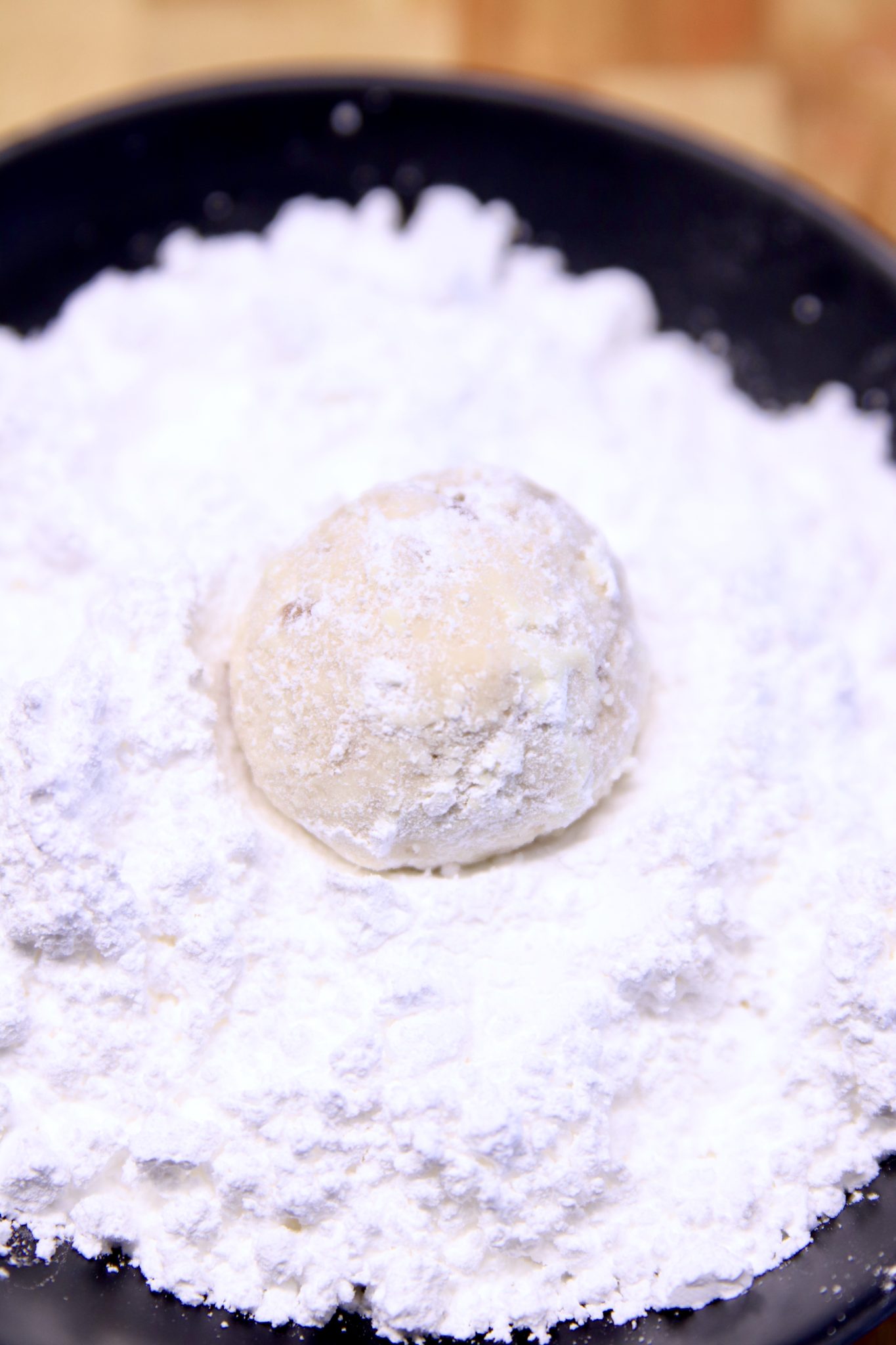 rolling cookie balls in powdered sugar