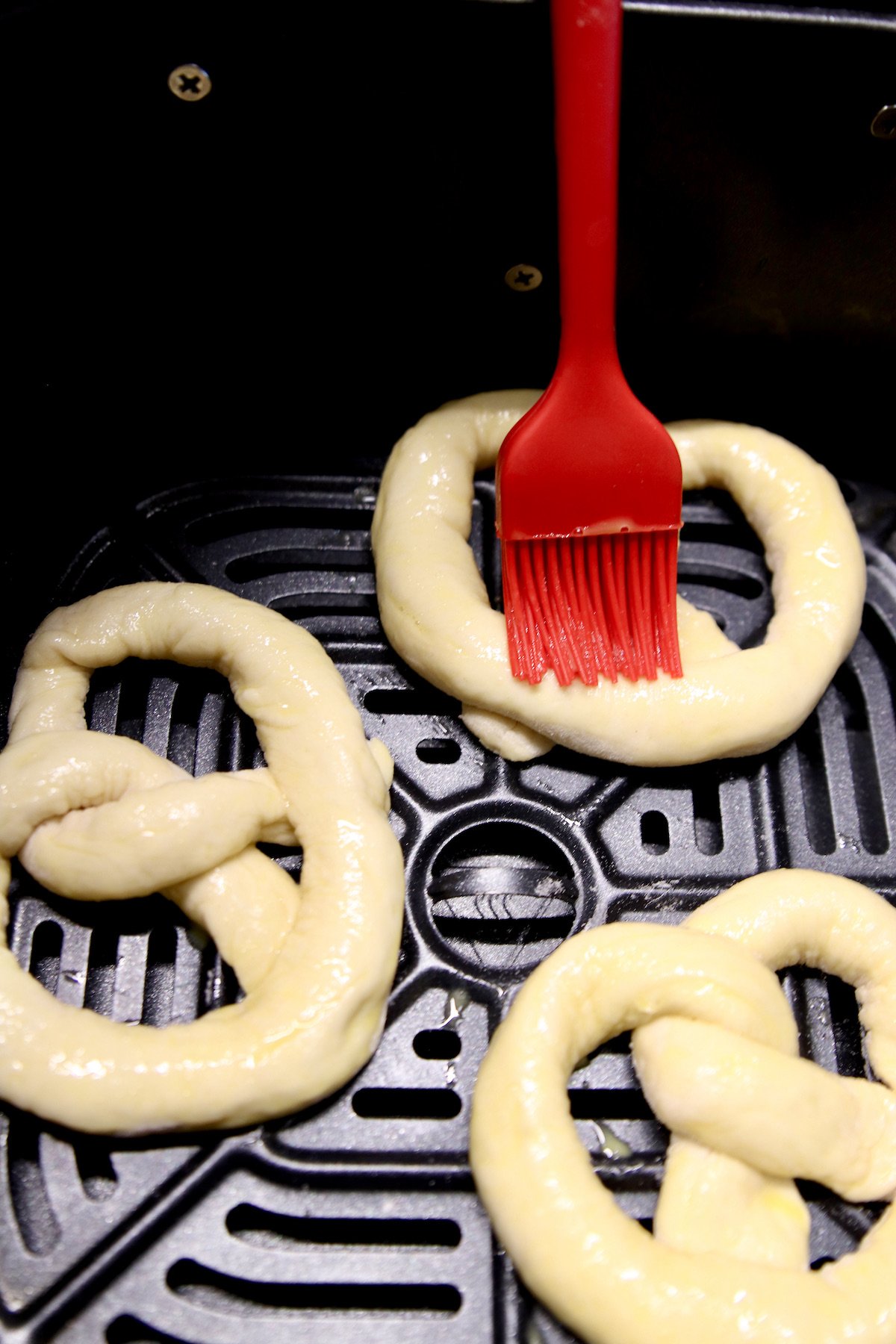 brushing pretzels in an air fryer with egg wash
