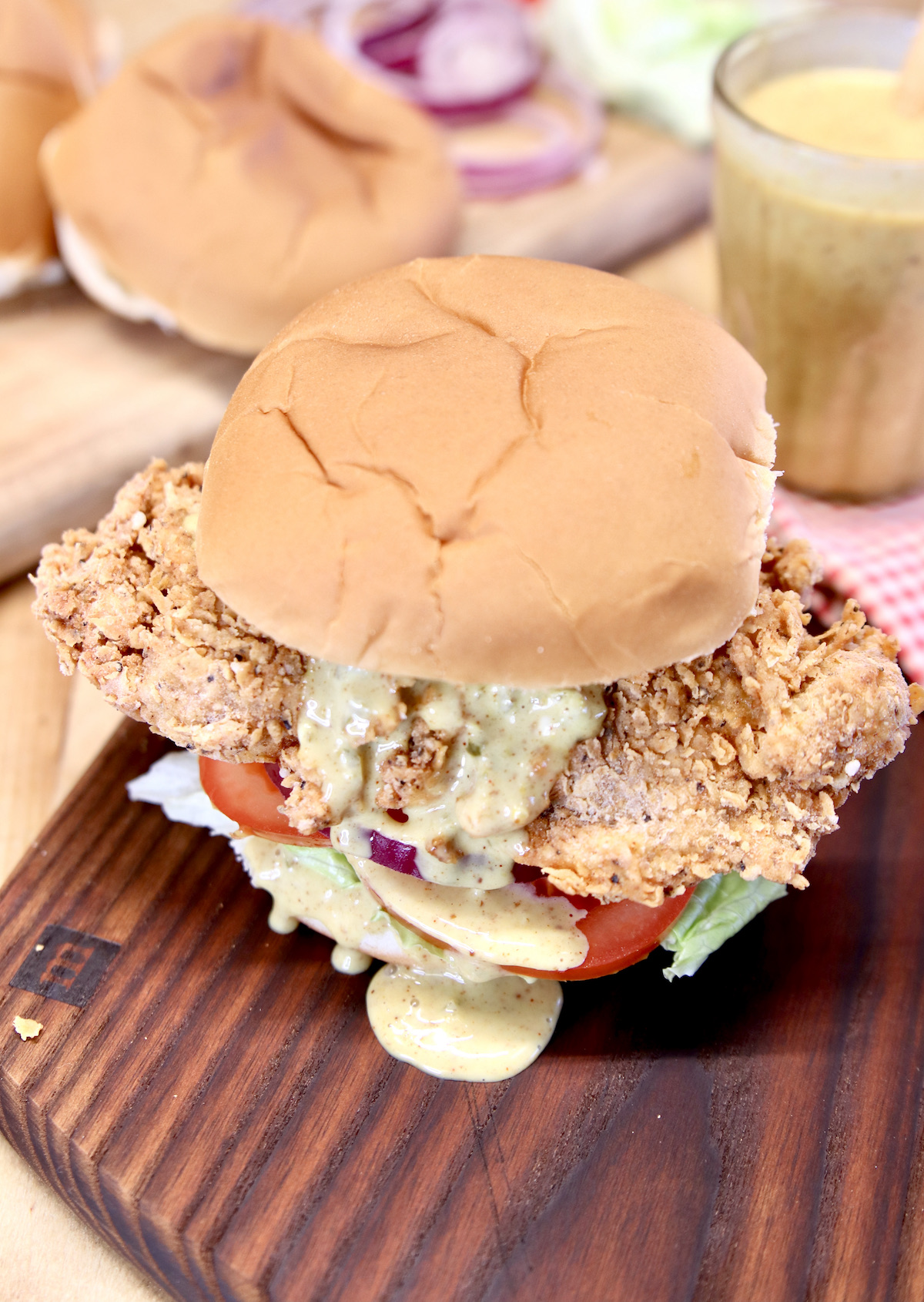 chicken tender sandwiches on a cutting board, sauce drizzling out. 
