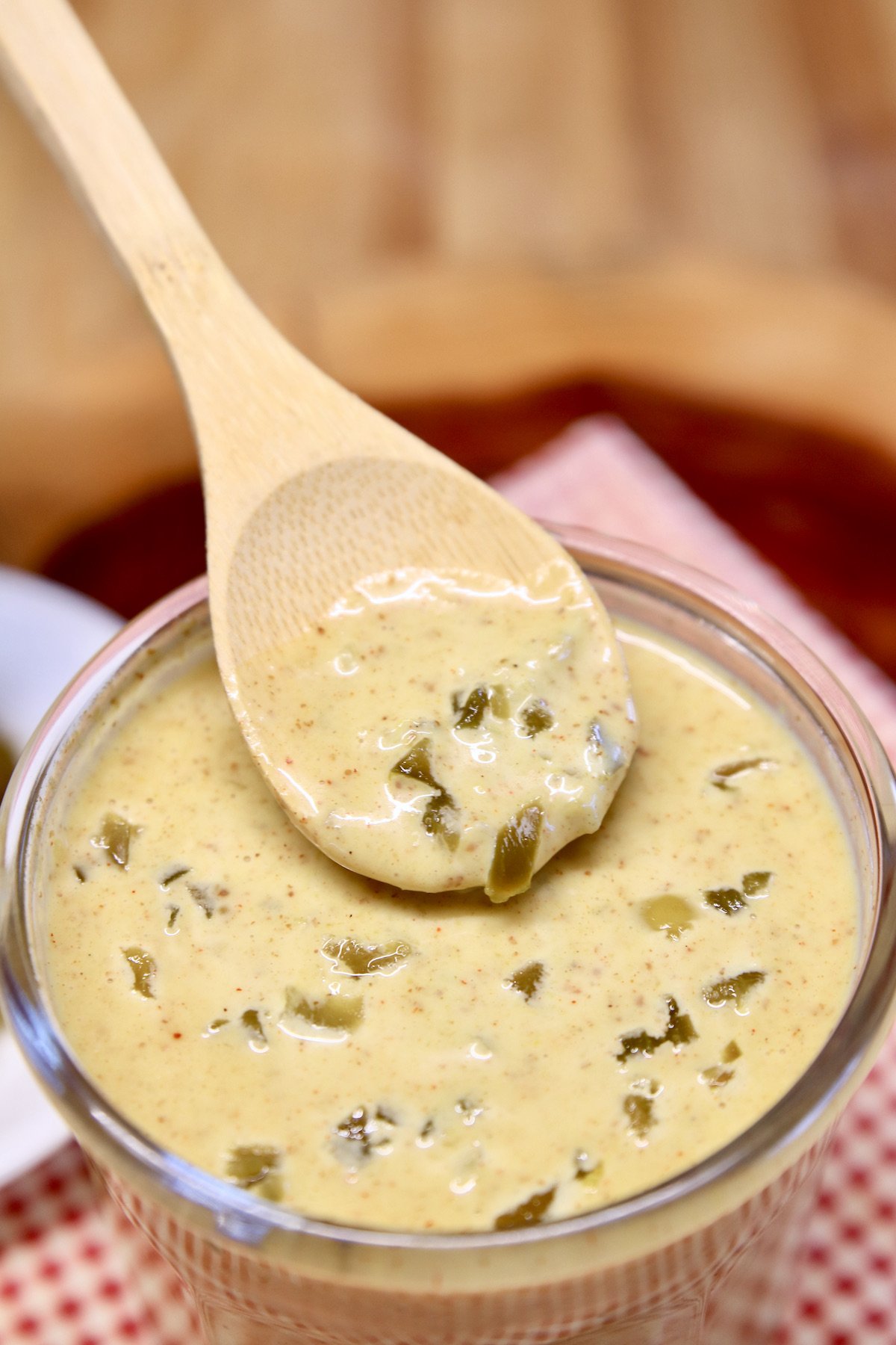 jalapeno honey mustard sauce on a spoon dipping from jar