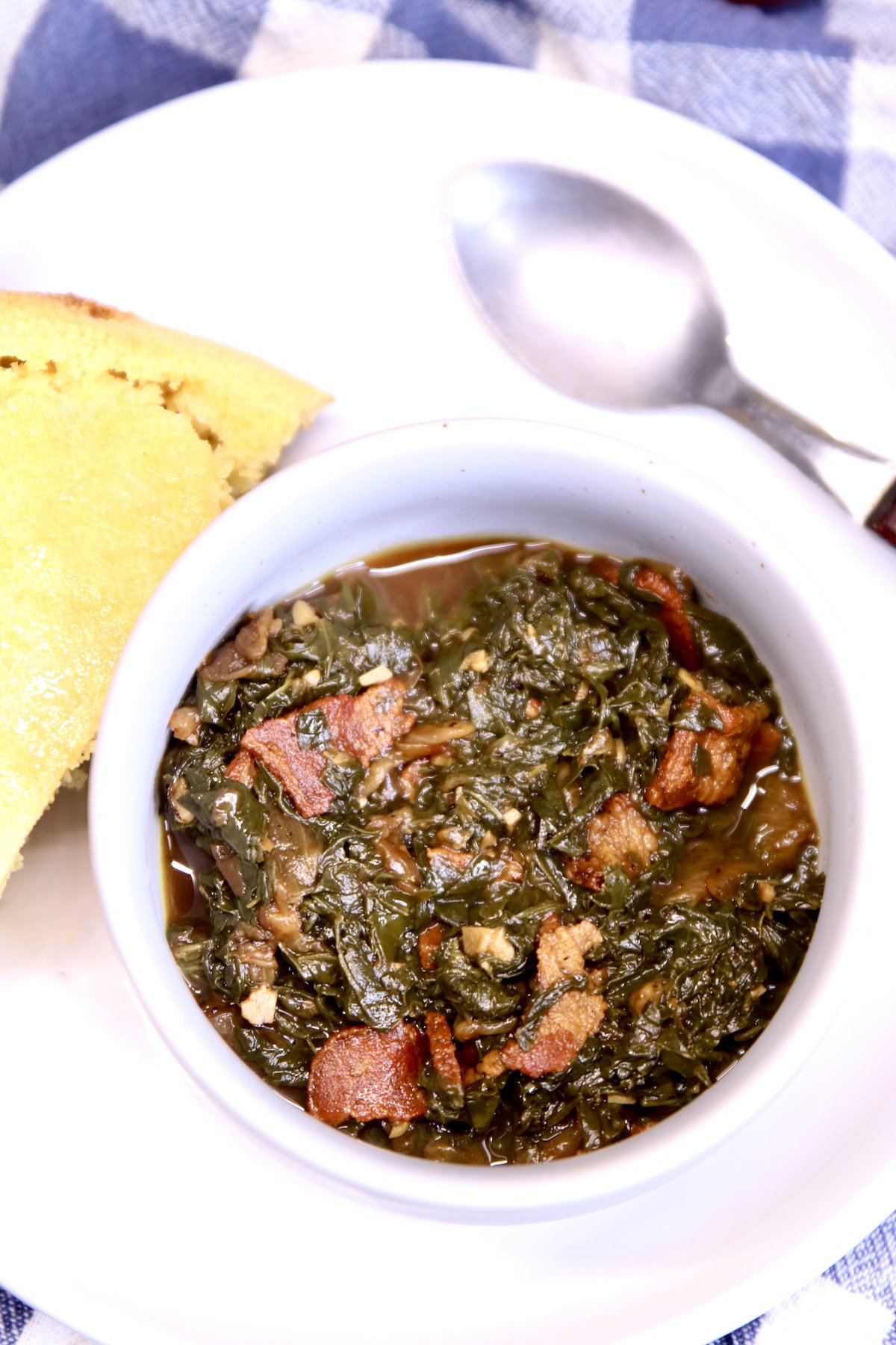 turnip greens with bacon in a bowl with cornbread and a spoon