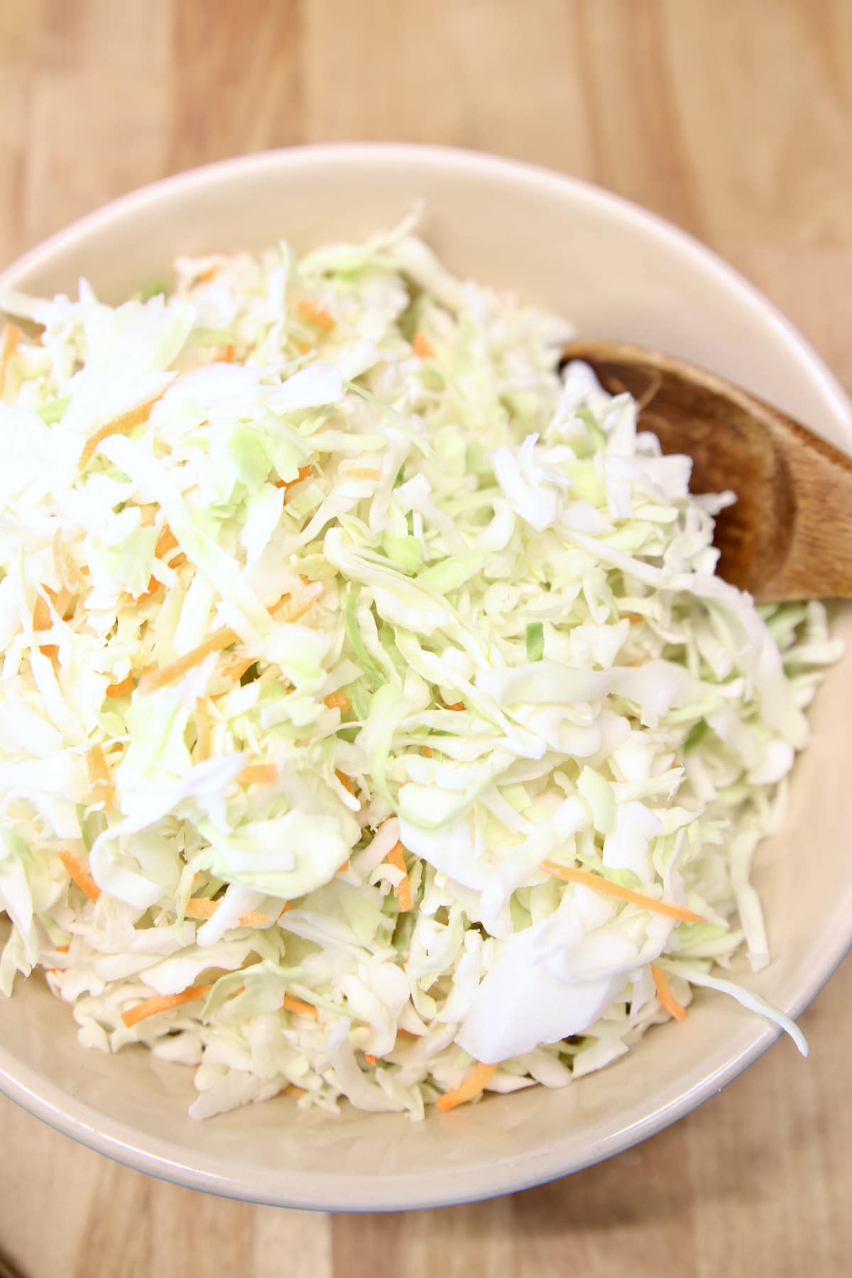 slaw mix in a bowl with wood spoon.