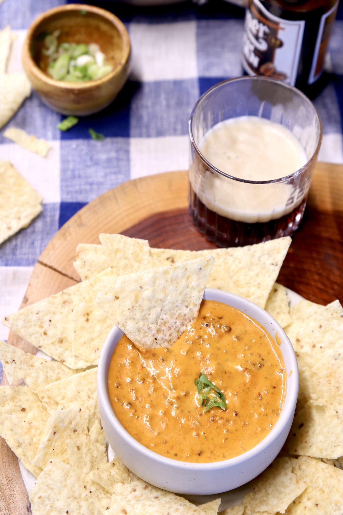 chili cheese dip in a bowl with tortilla chips and glass of beer