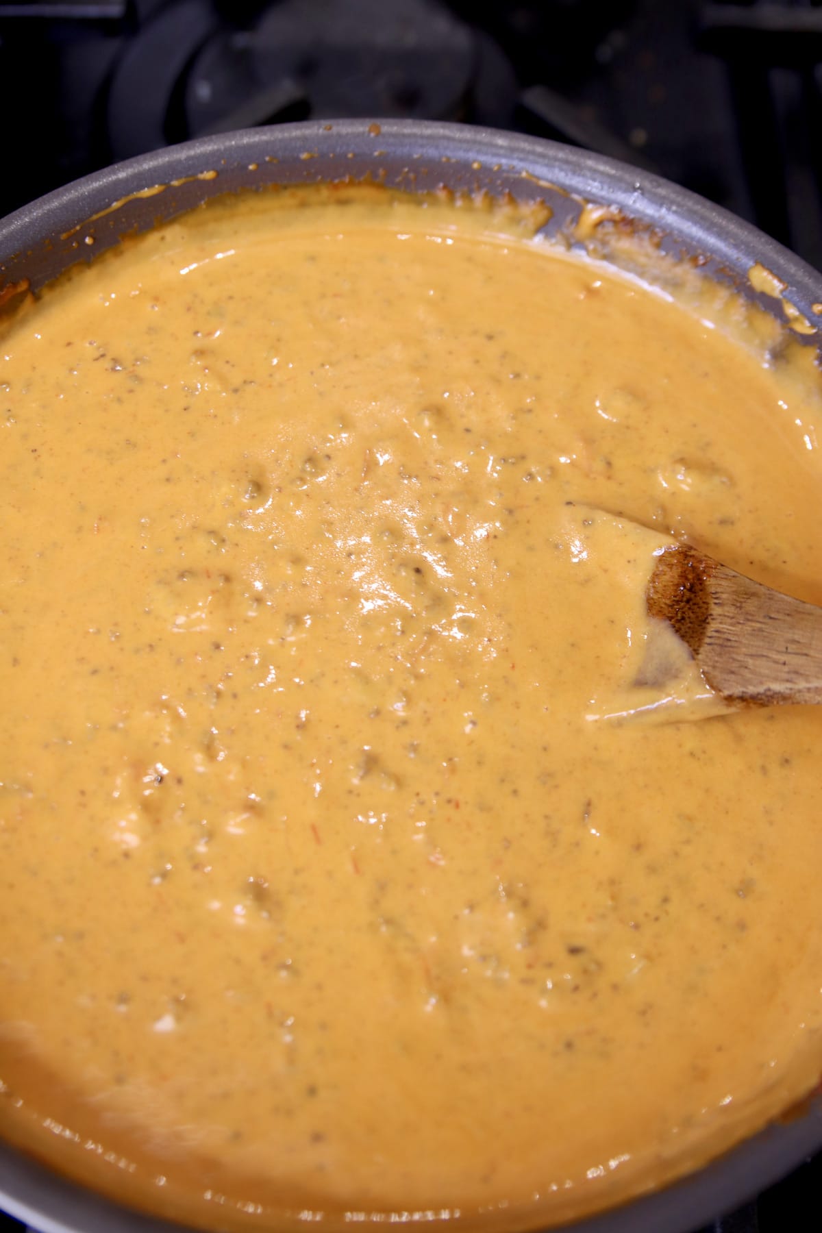 chili cheese dip in a pan with wooden spoon.