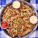 duck fat oven fries on a platter with 3 dipping sauces