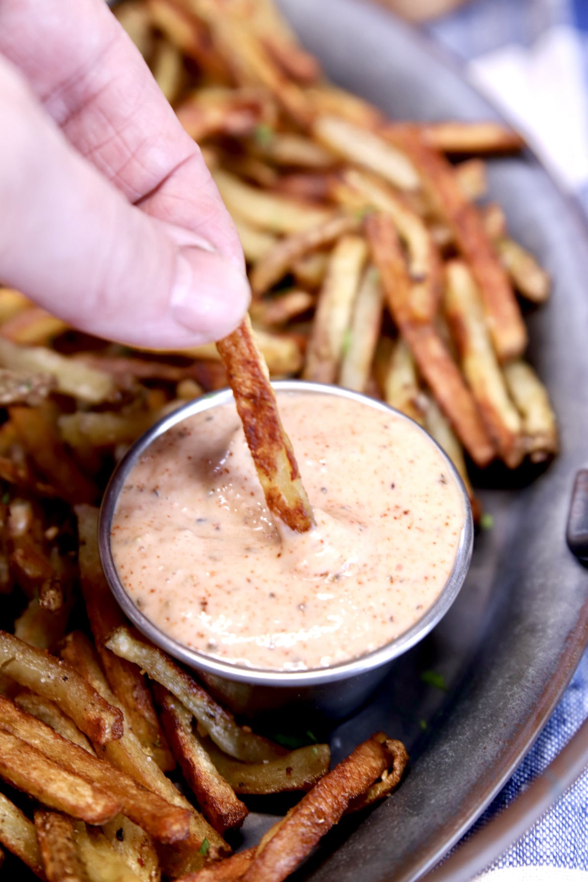 dipping fries in sauce on a tray.