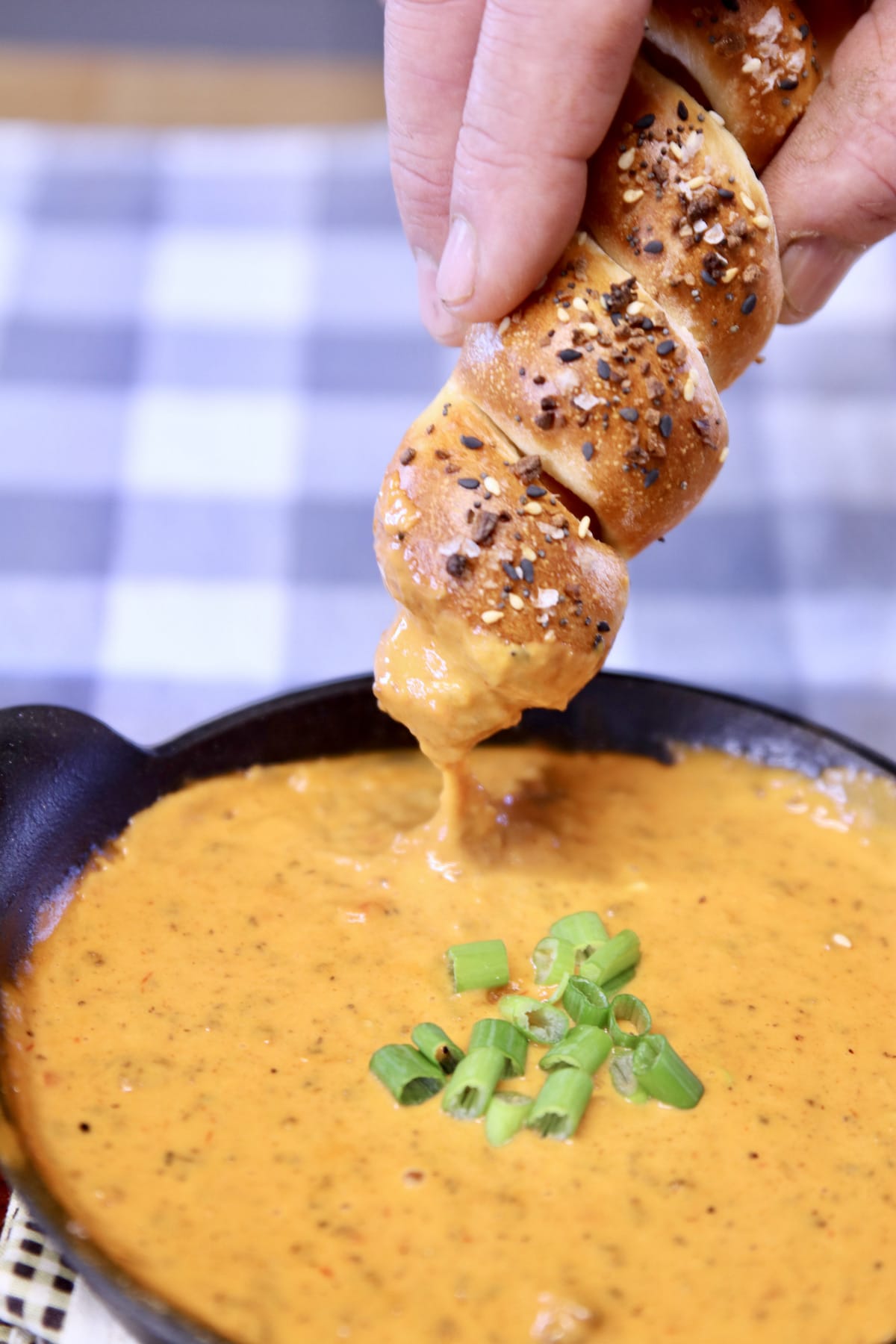 pretzel dog dipping into chili cheese dip