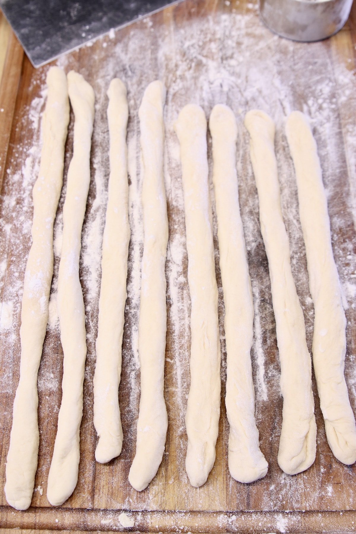 8 dough ropes on a cutting board for pretzel dogs.
