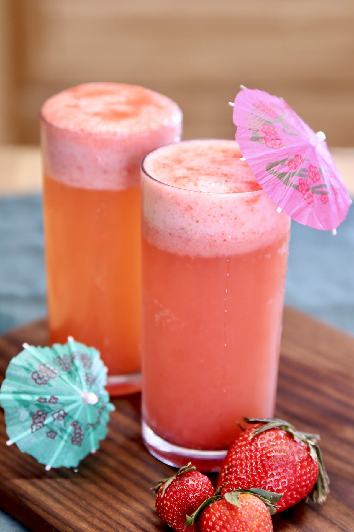 2 glasses of strawberry shandy cocktails with drink umbrellas.
