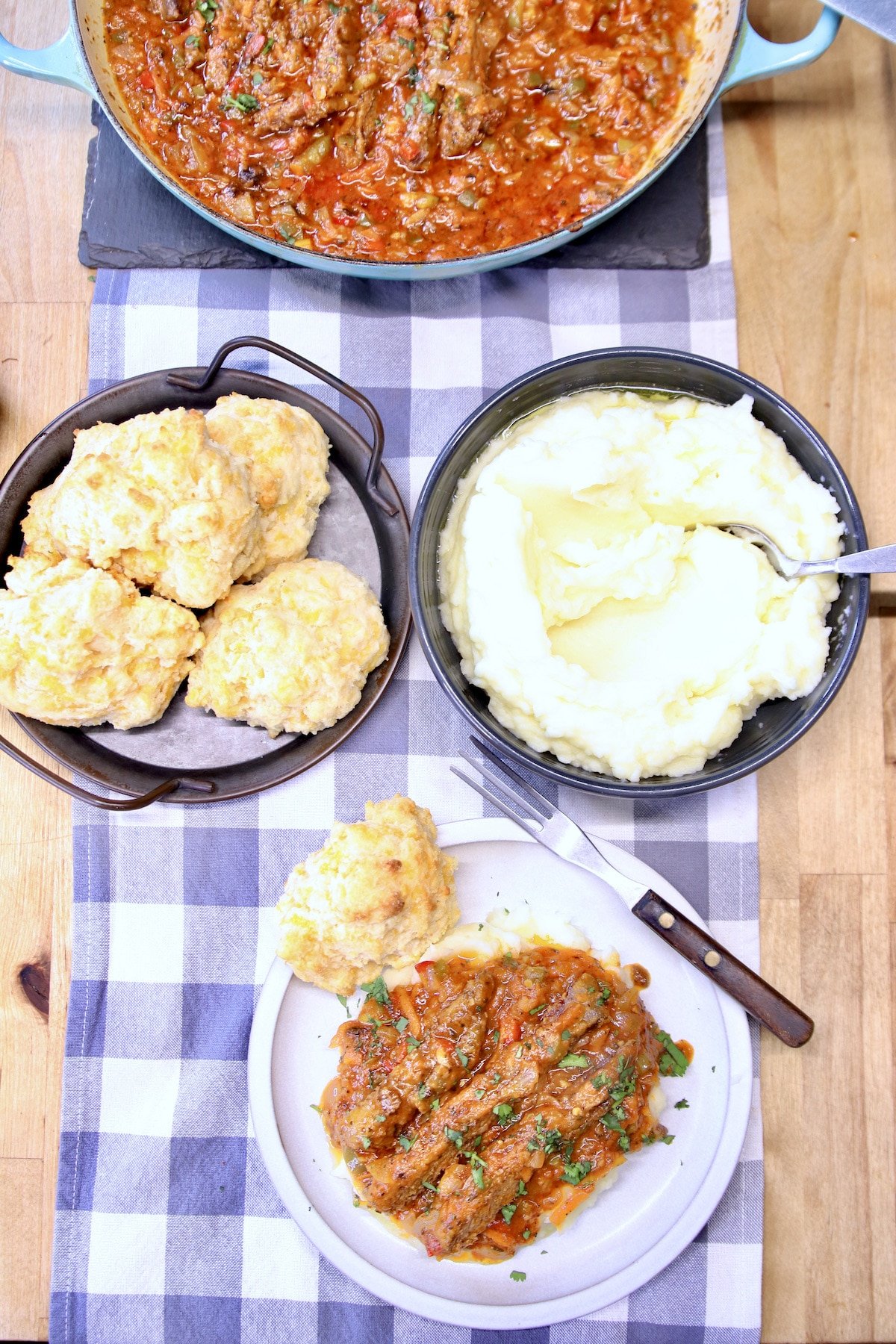 Swiss Steak on a plate with mashed potatoes, biscuits.