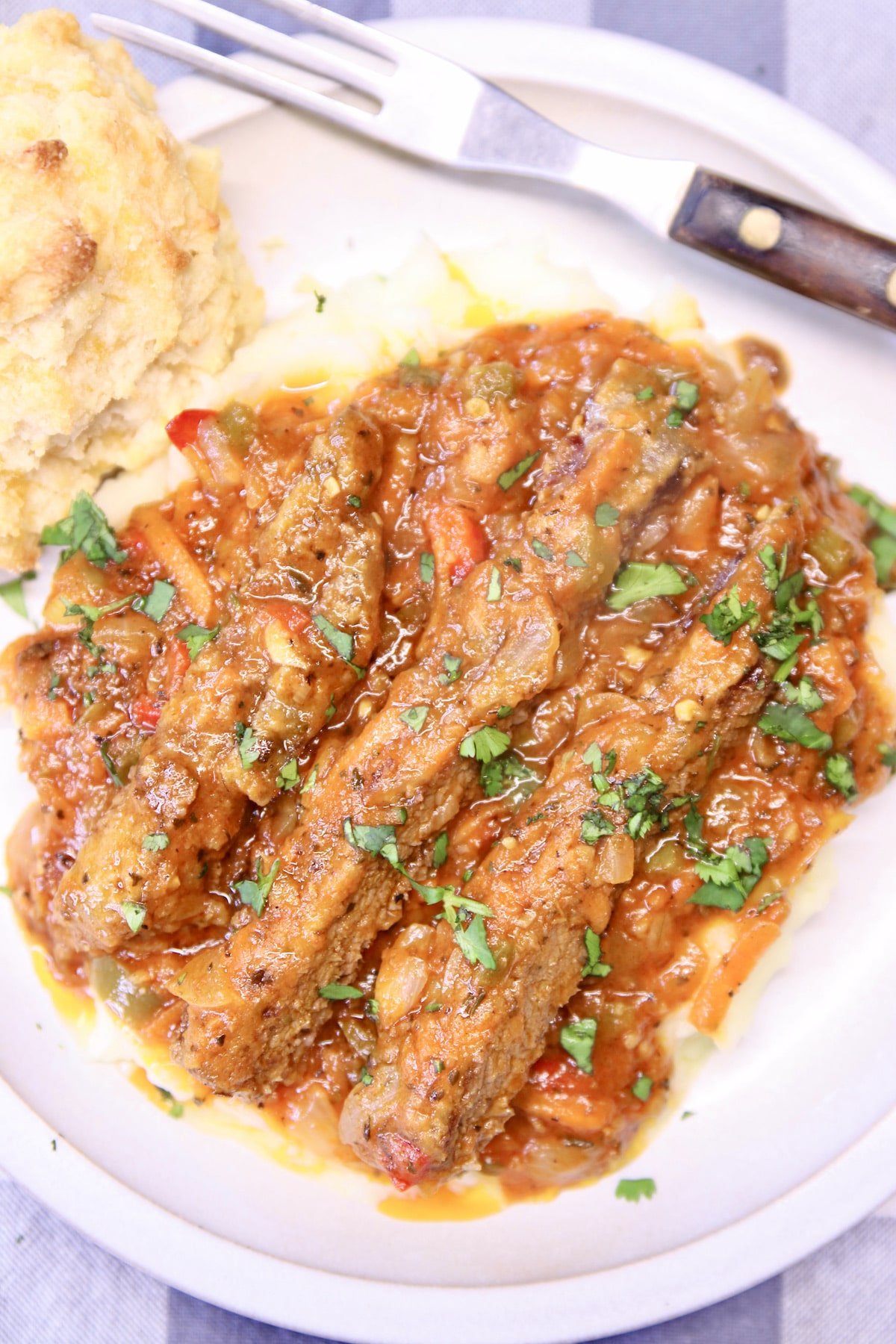 Swiss Steak over mashed potatoes on a plate - close up.