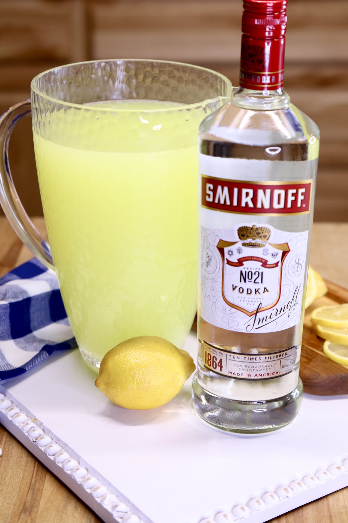 Pitcher of lemonade, bottle of Smirnoff vodka and a whole lemon on a white board.