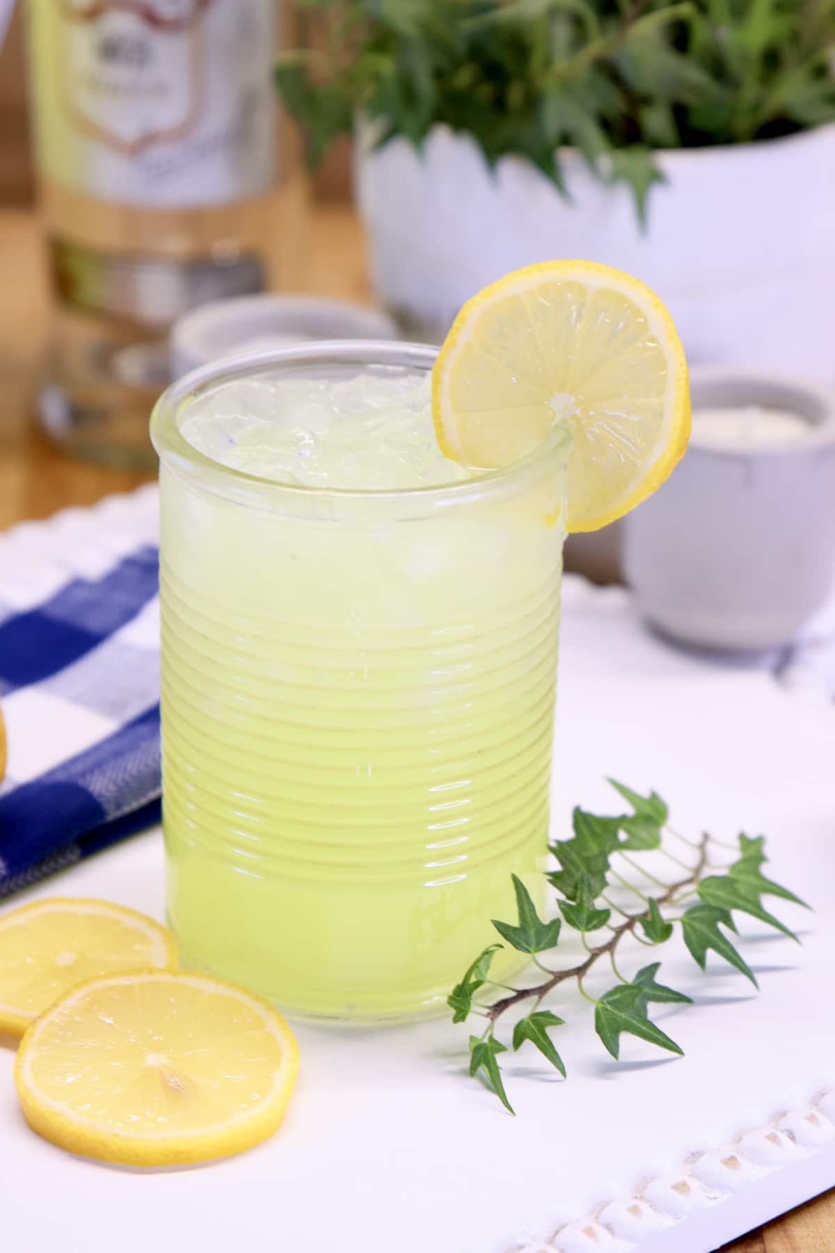 vodka lemonade in a glass with lemon garnish. Ivy in background.
