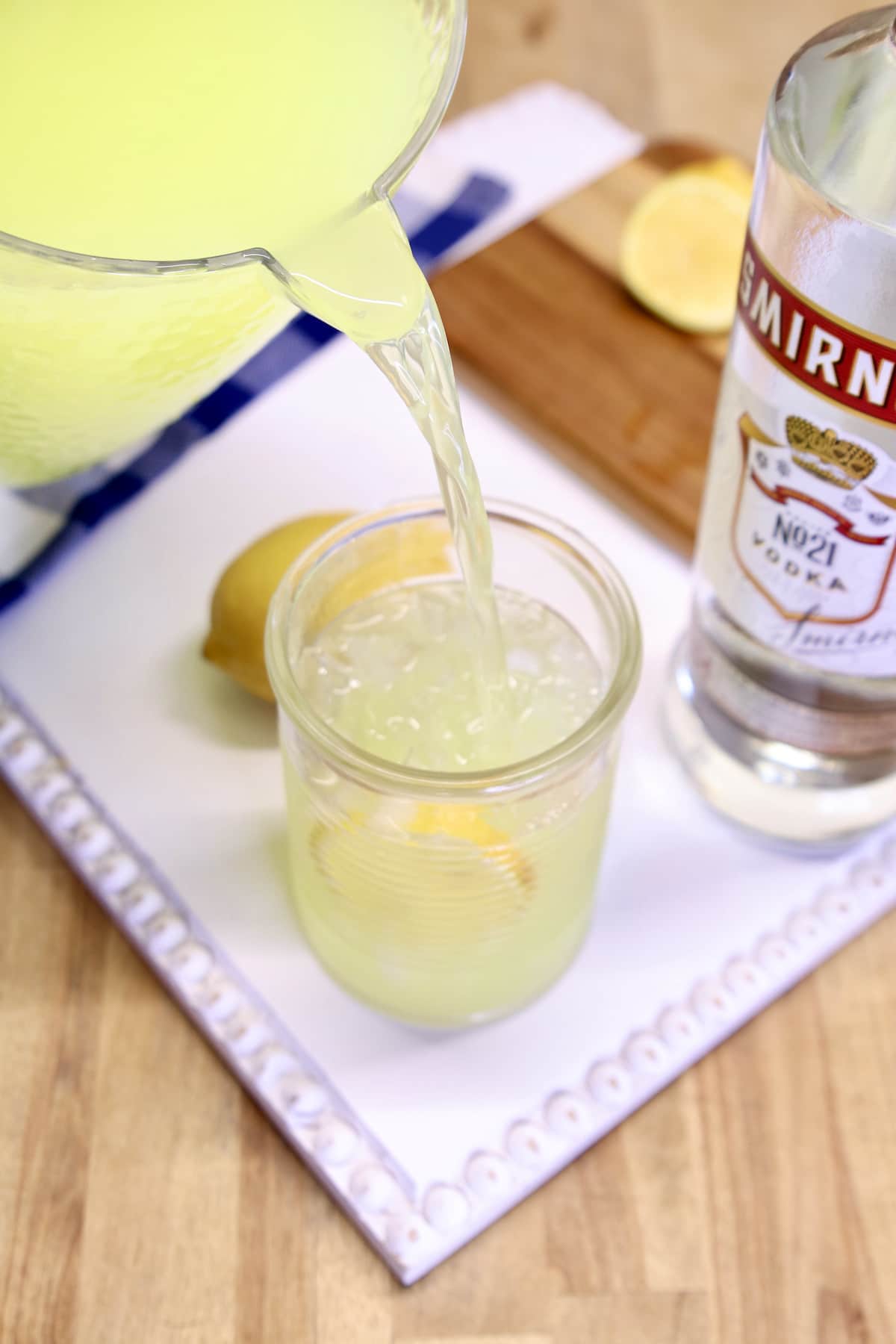 Pouring lemonade into a glass with vodka and ice.