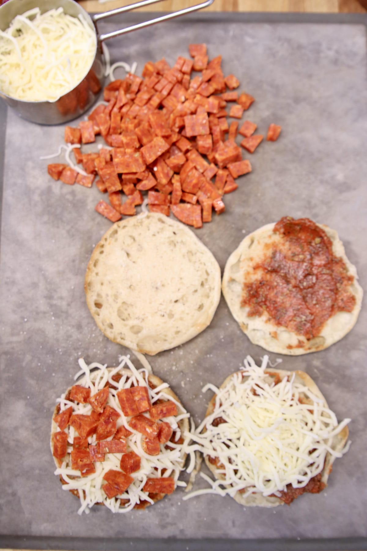 Topping English muffins with pizza toppings.