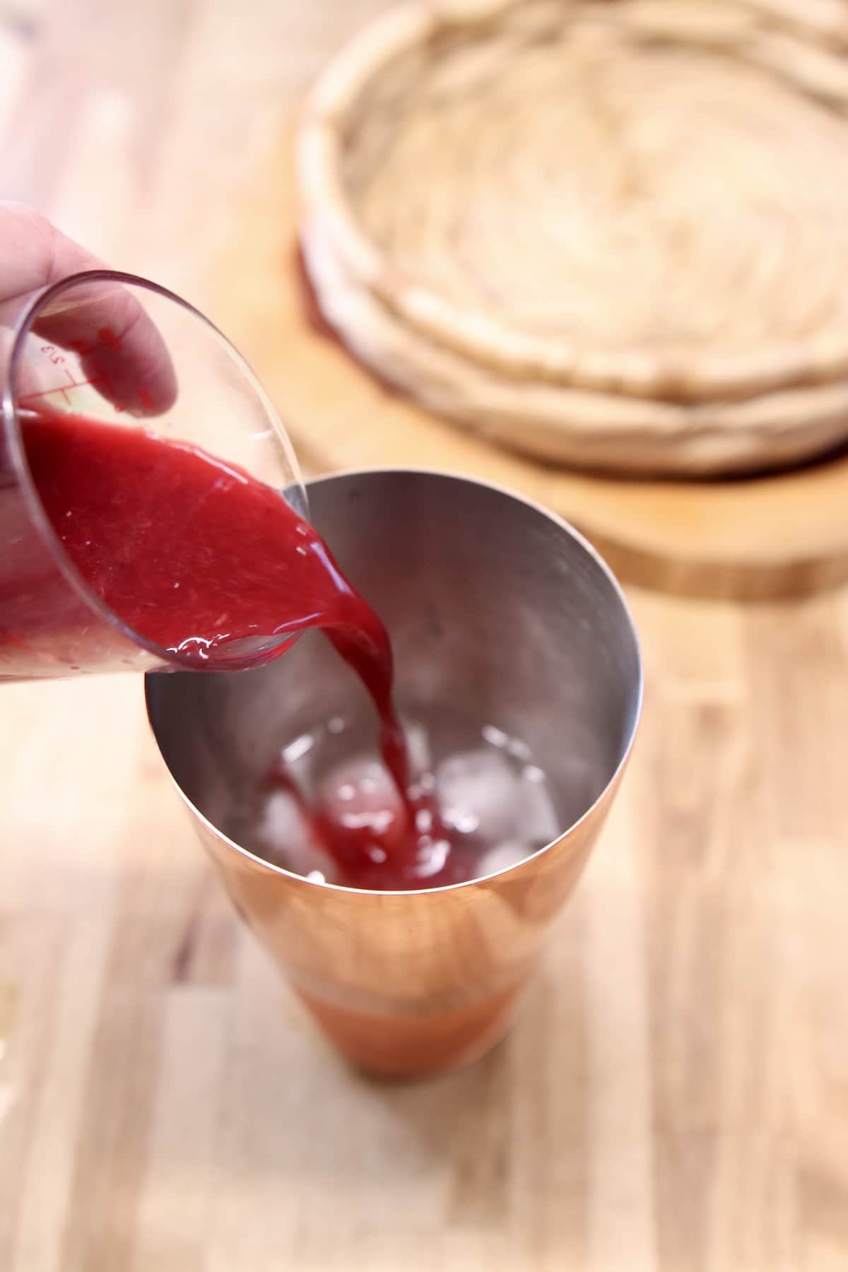 Pouring blood orange juice into a cocktail shaker.