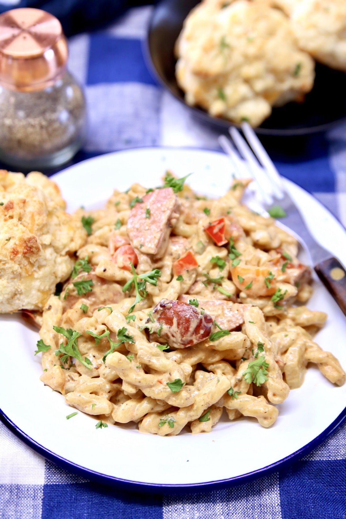Creamy Cajun Sausage Pasta on a plate with cheddar biscuit.