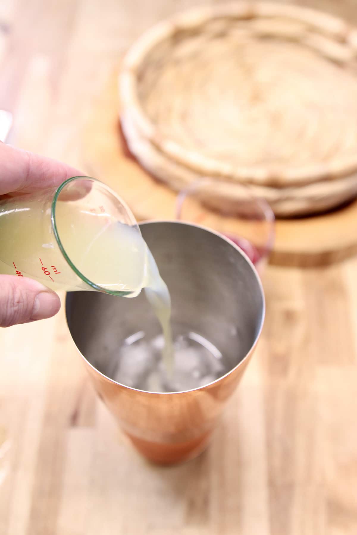 pouring lime juice into cocktail shaker.