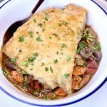 Steak and mushroom pot pie with puff pastry crust in a bowl.