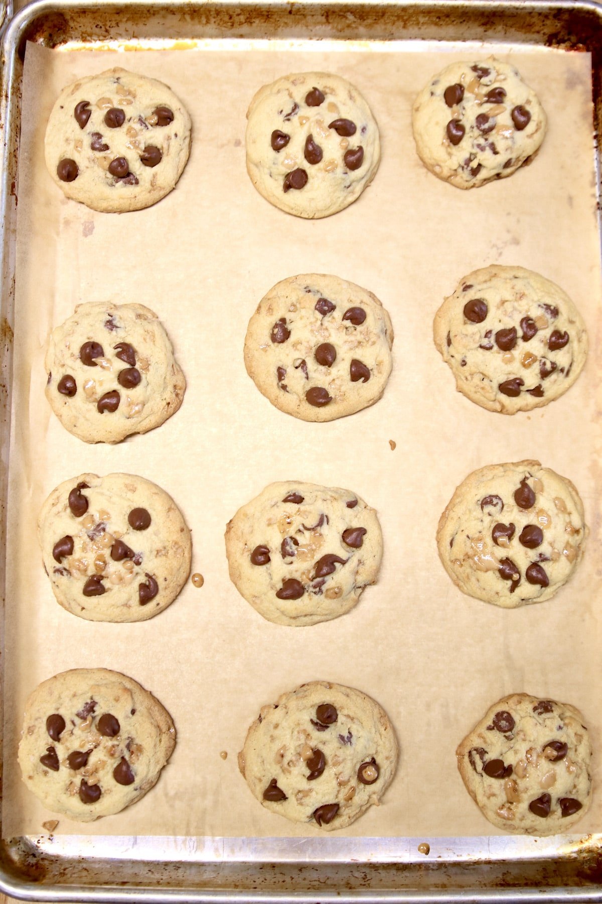 Baked chocolate chip cookies on parchment lined cookie sheet.