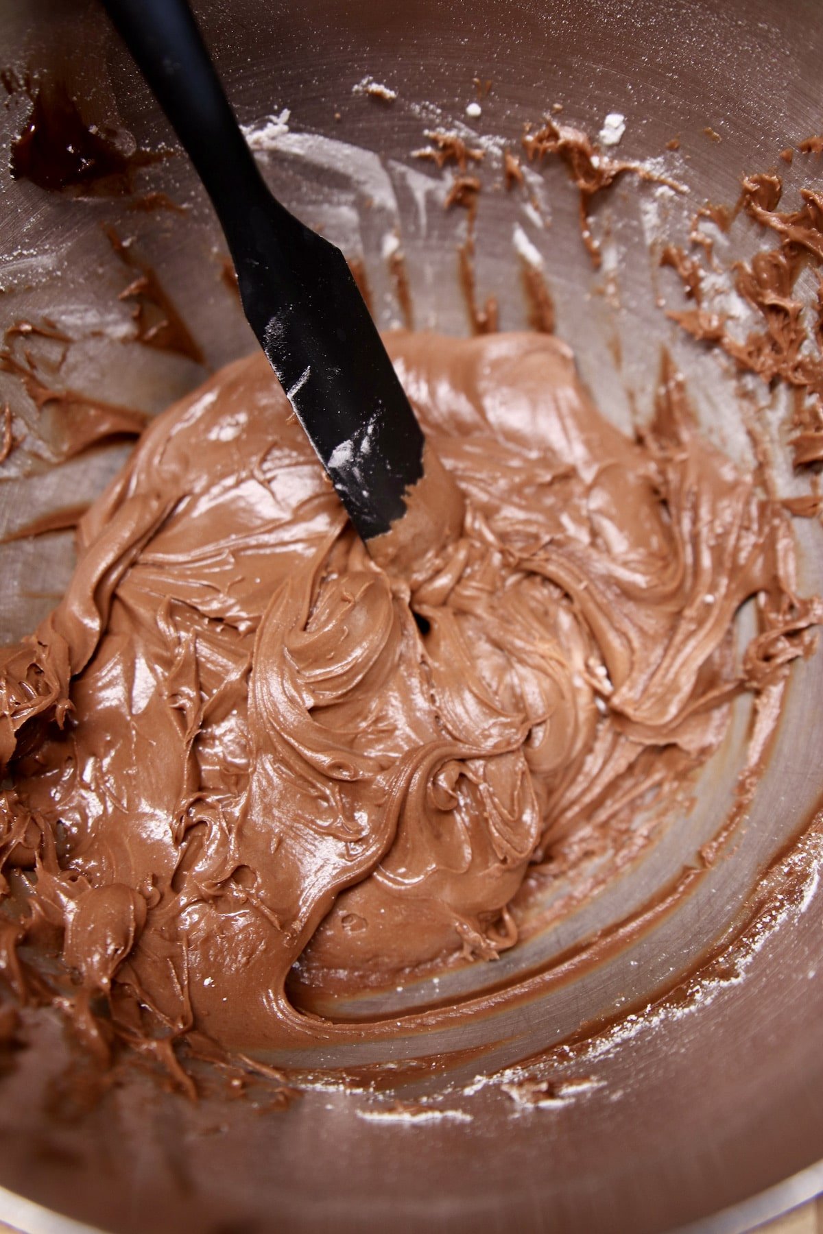 Chocolate frosting in a bowl with spatula.