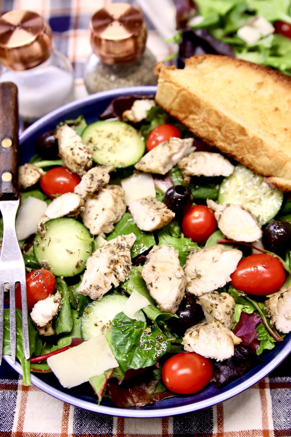 Bowl of grilled chicken salad and garlic bread.