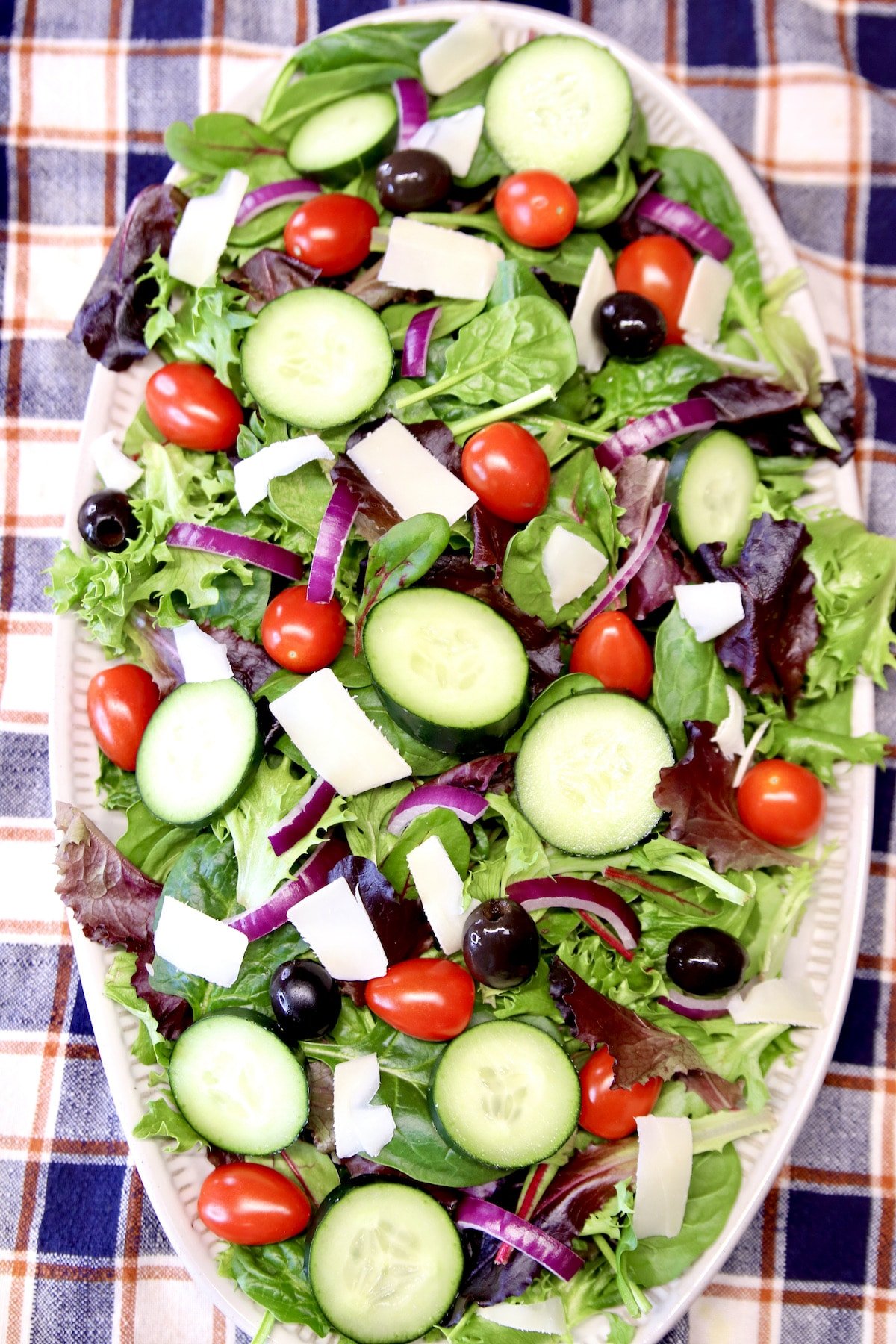 Platter with salad greens, tomatoes, olives, parmesan cheese.d