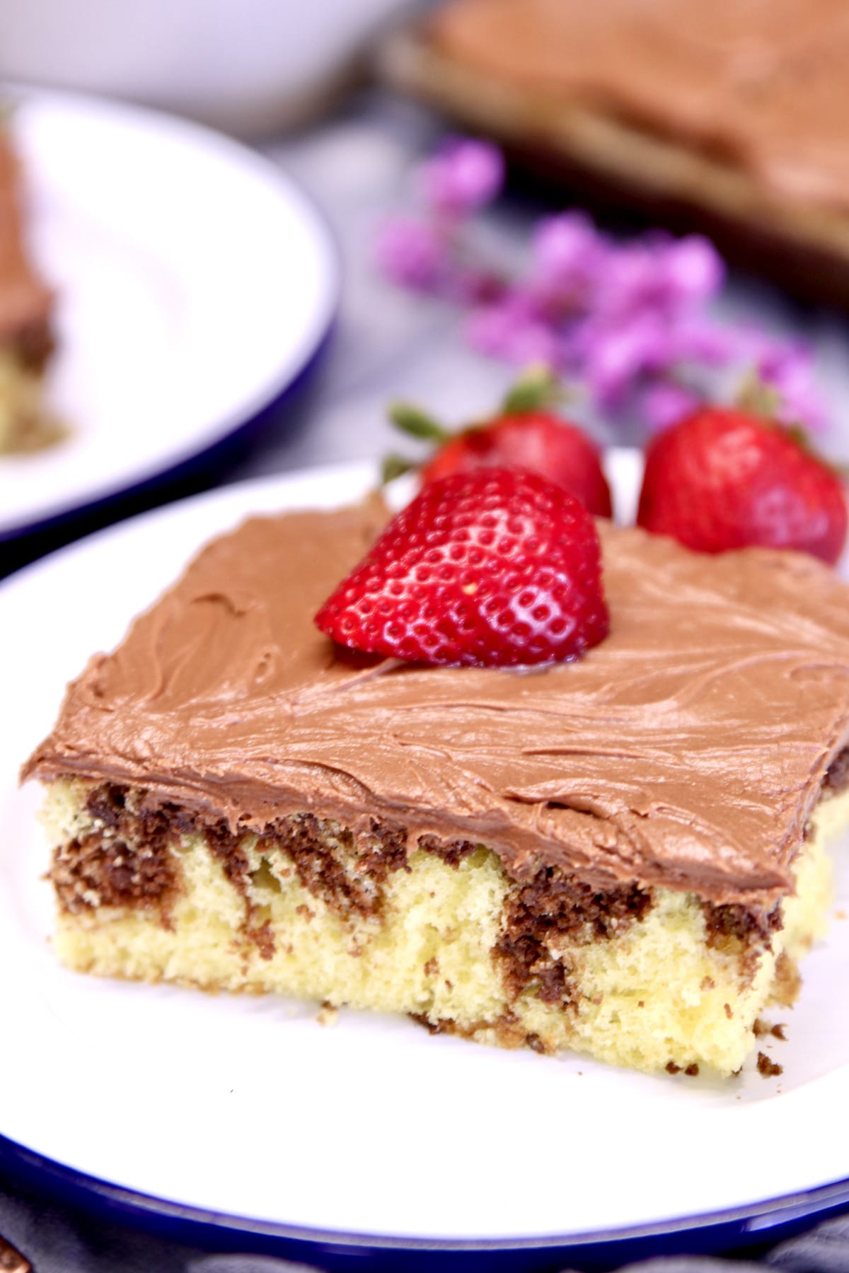 Marble Sheet Cake slice with chocolate icing and half strawberry.