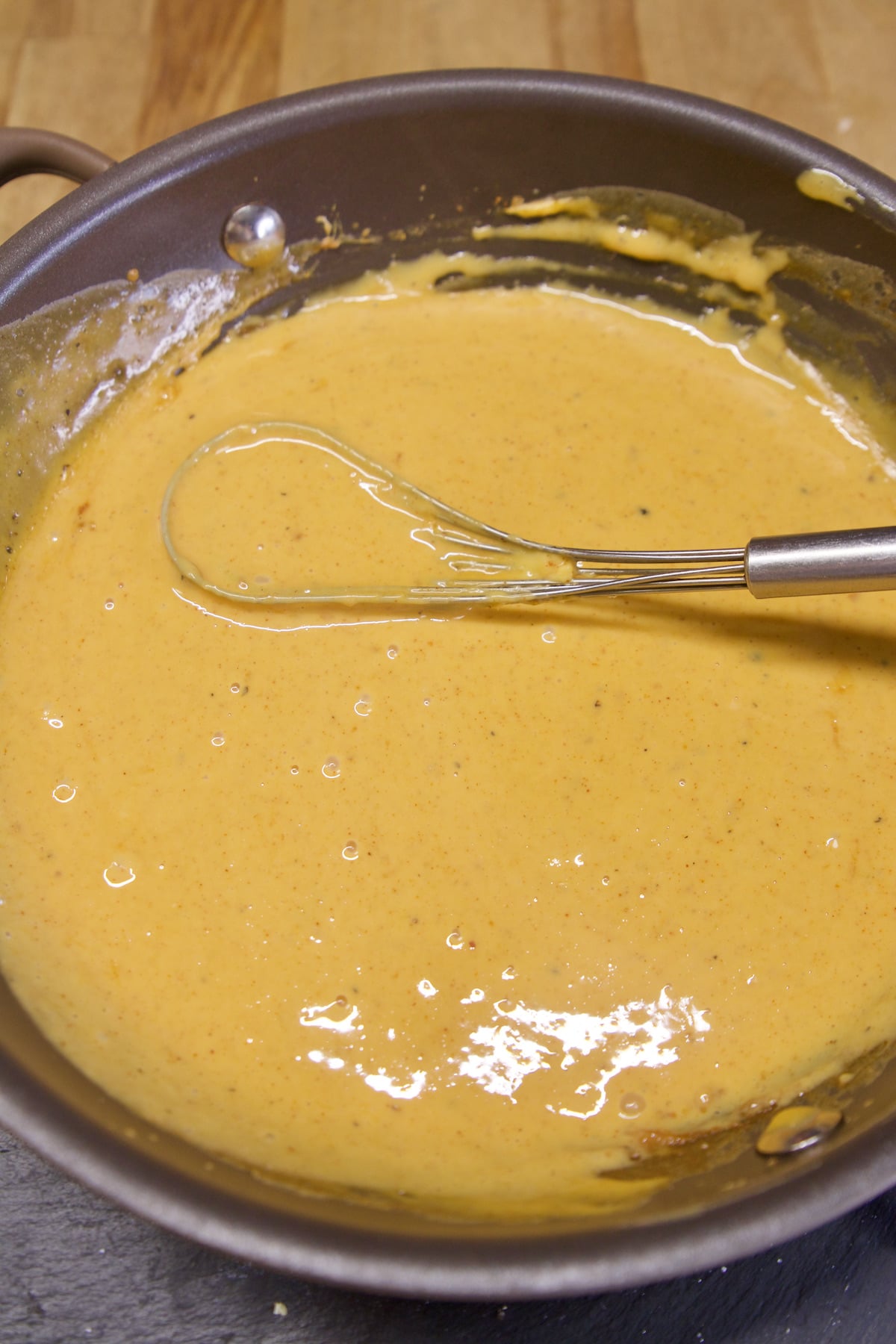 Velveeta cheese sauce in a pan with whisk.