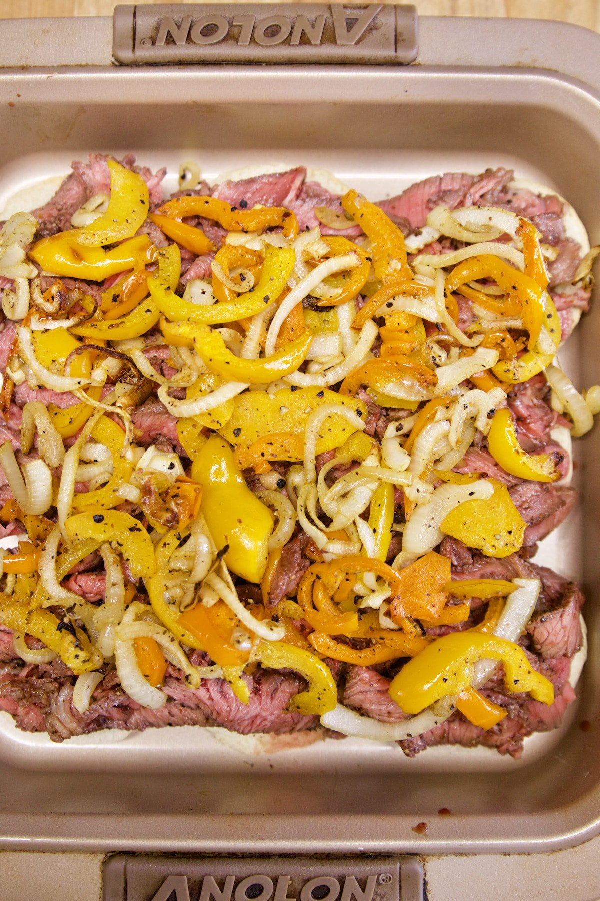 Pan of sliders with steak, peppers, onions.