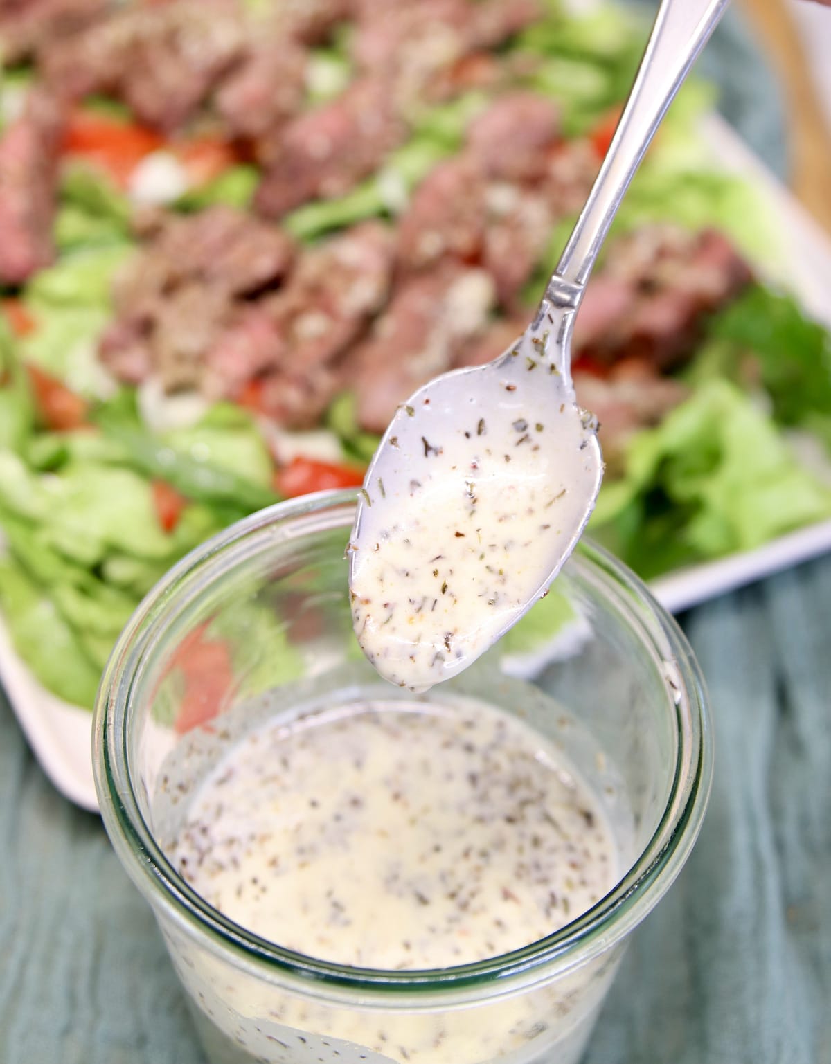 Spoon of Creamy Italian Salad Dressing dipping from jar.