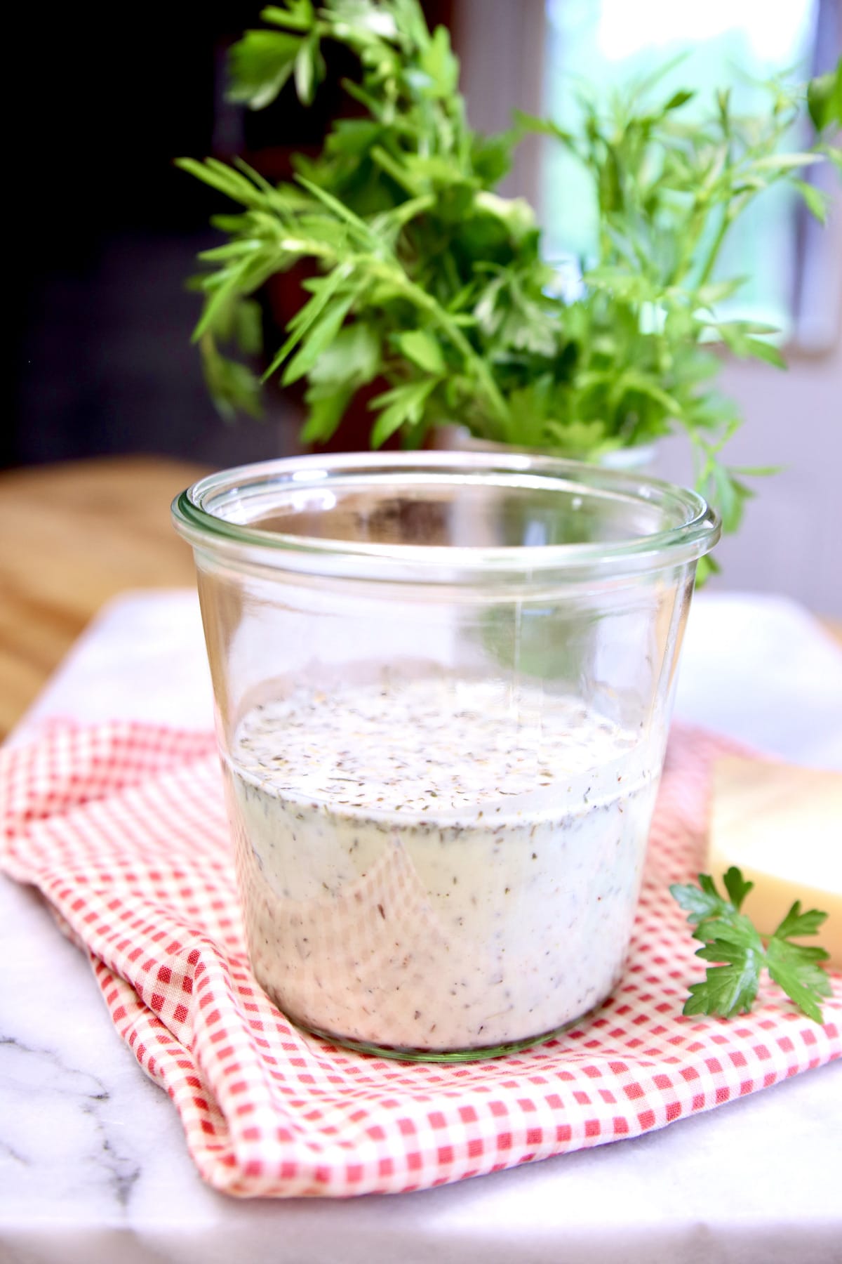 Creamy Italian Salad Dressing in a jar, fresh parsley in background.