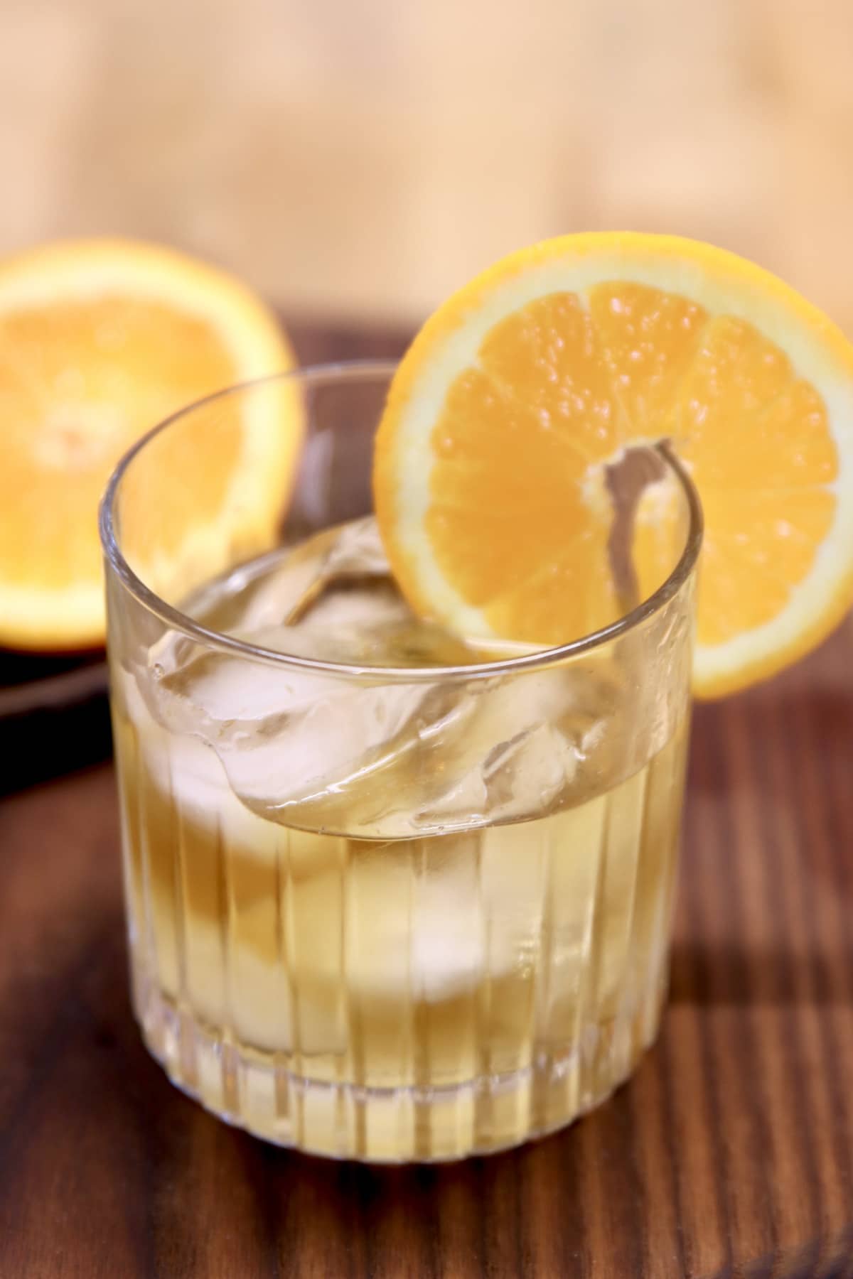 Whiskey cocktail with orange wheel garnish.