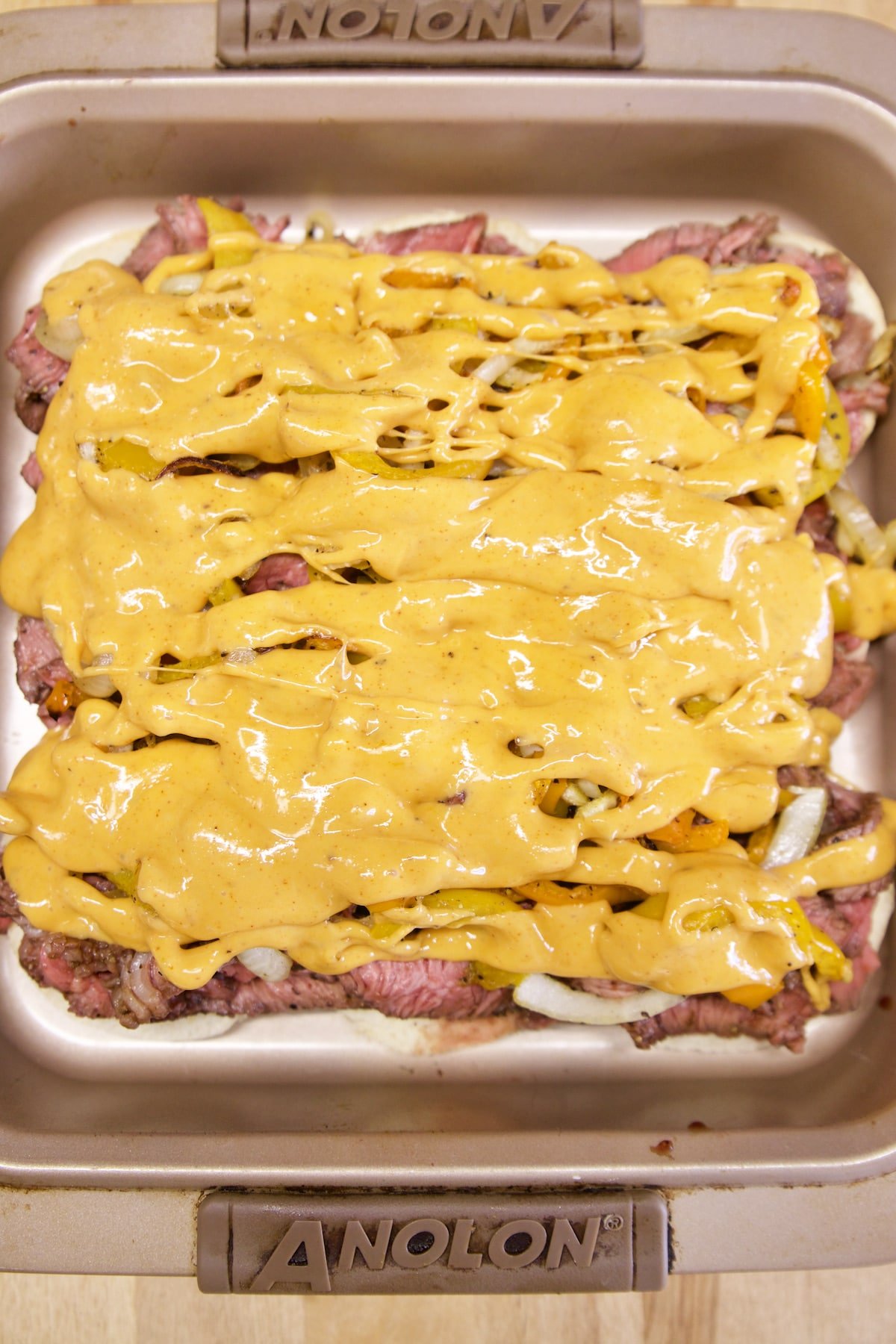 Cheese sauce drizzled over steak, peppers, onions.