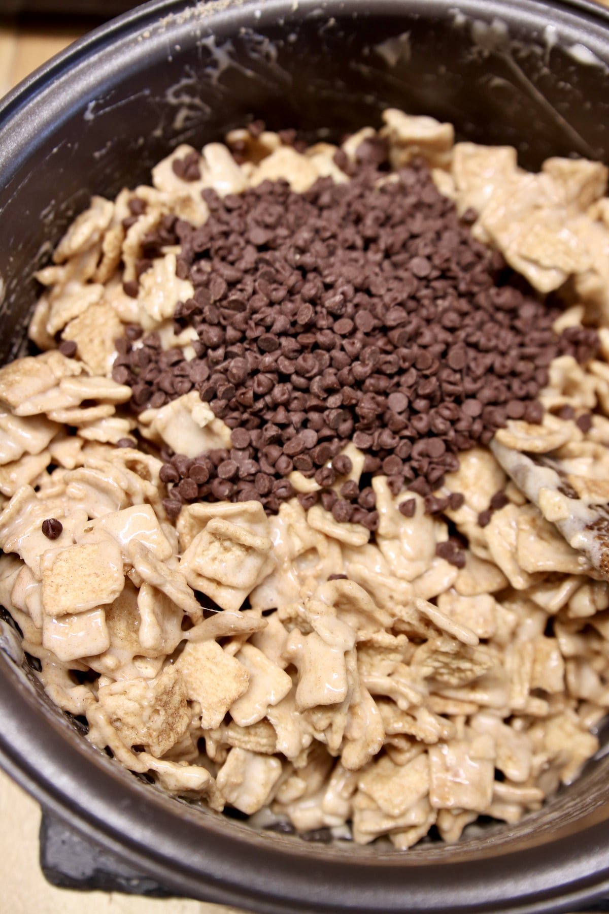 Adding chocolate chips to cereal marshmallow treats.