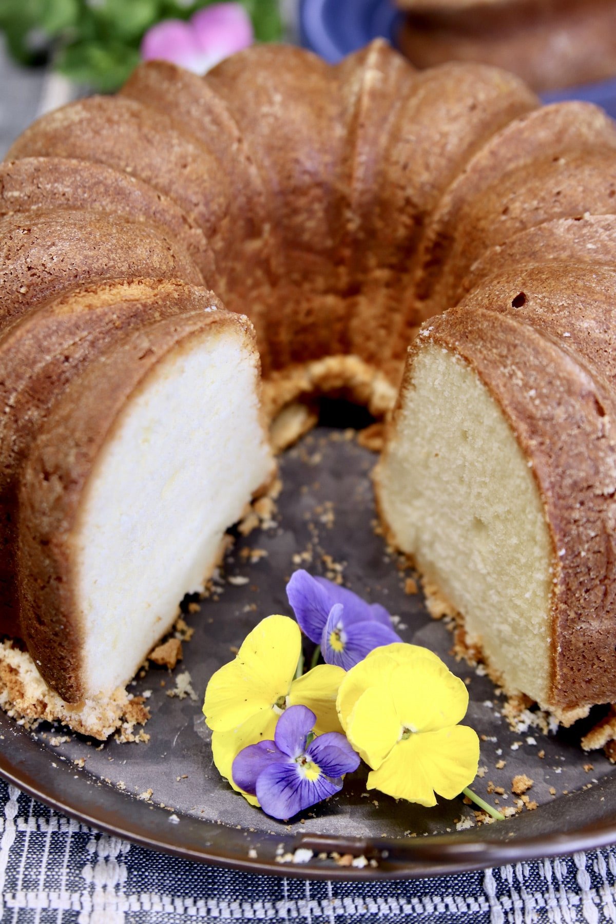 Pound Cake with one slice out, pansy flowers on the platter.