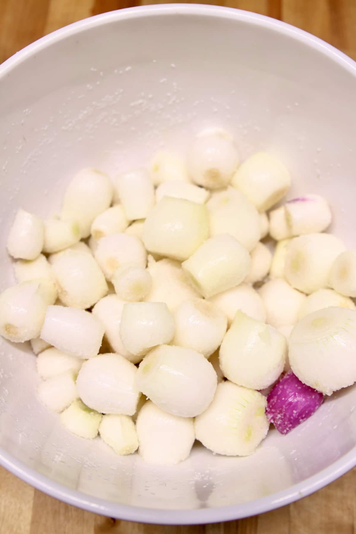 Onions in a bowl with kosher salt.